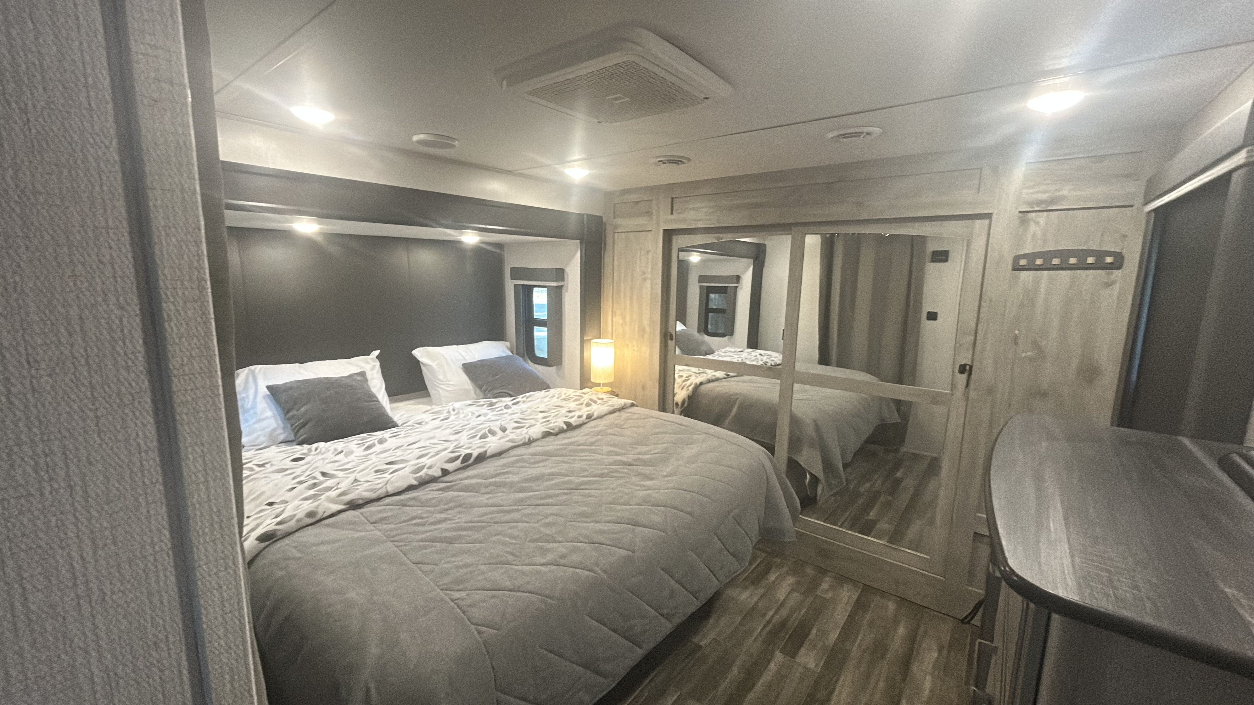Cozy RV rental bedroom featuring a large bed, mirrored closet, and contemporary design with ceiling lights and wood-look floor.. Keystone RV Avalanche 2022