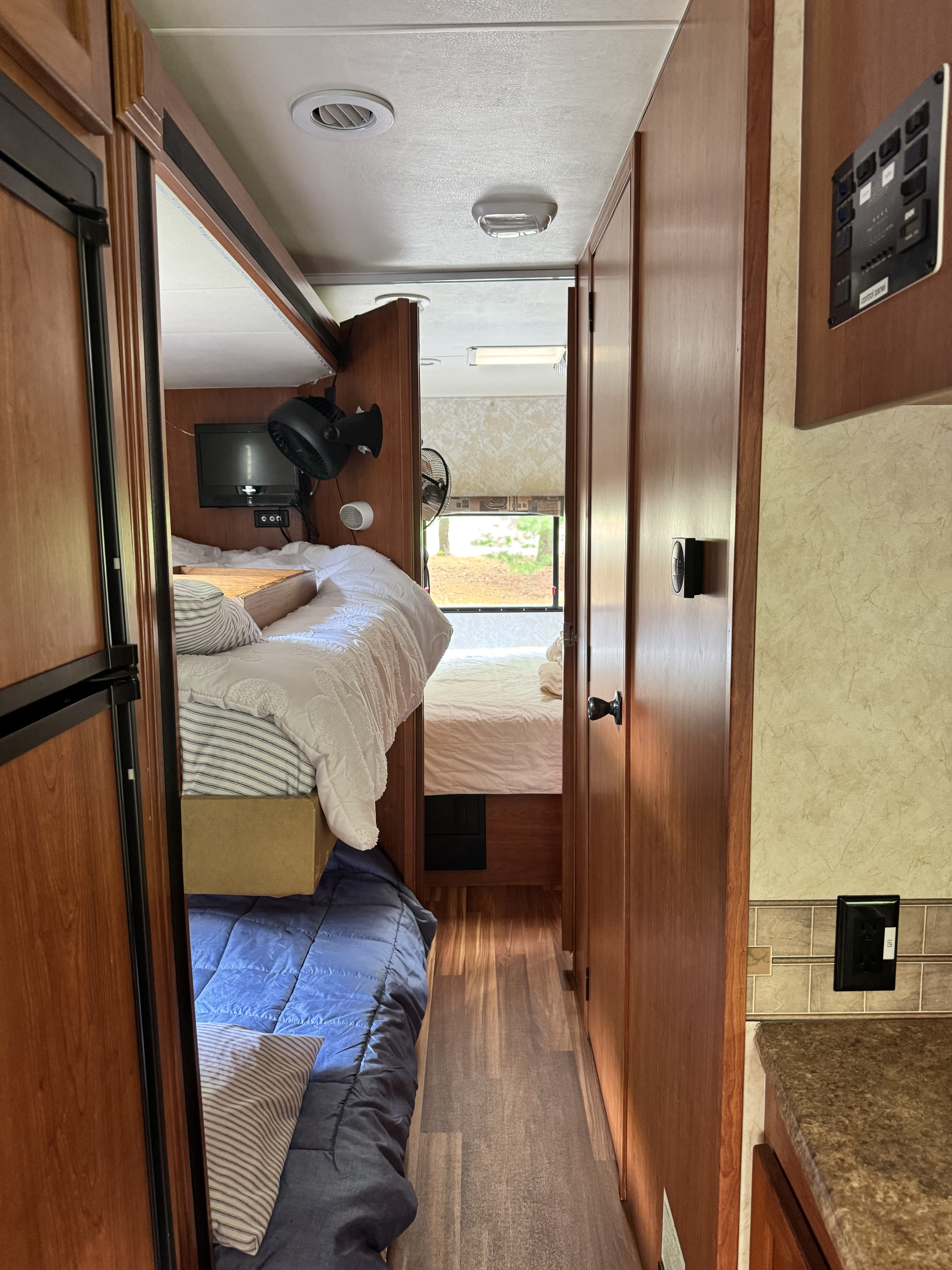 RV rental interior: cozy bunk beds, a central hallway leading to a bedroom, and wood accents. Control panel visible on right.. Forest River Coachmen Leprechaun 2013