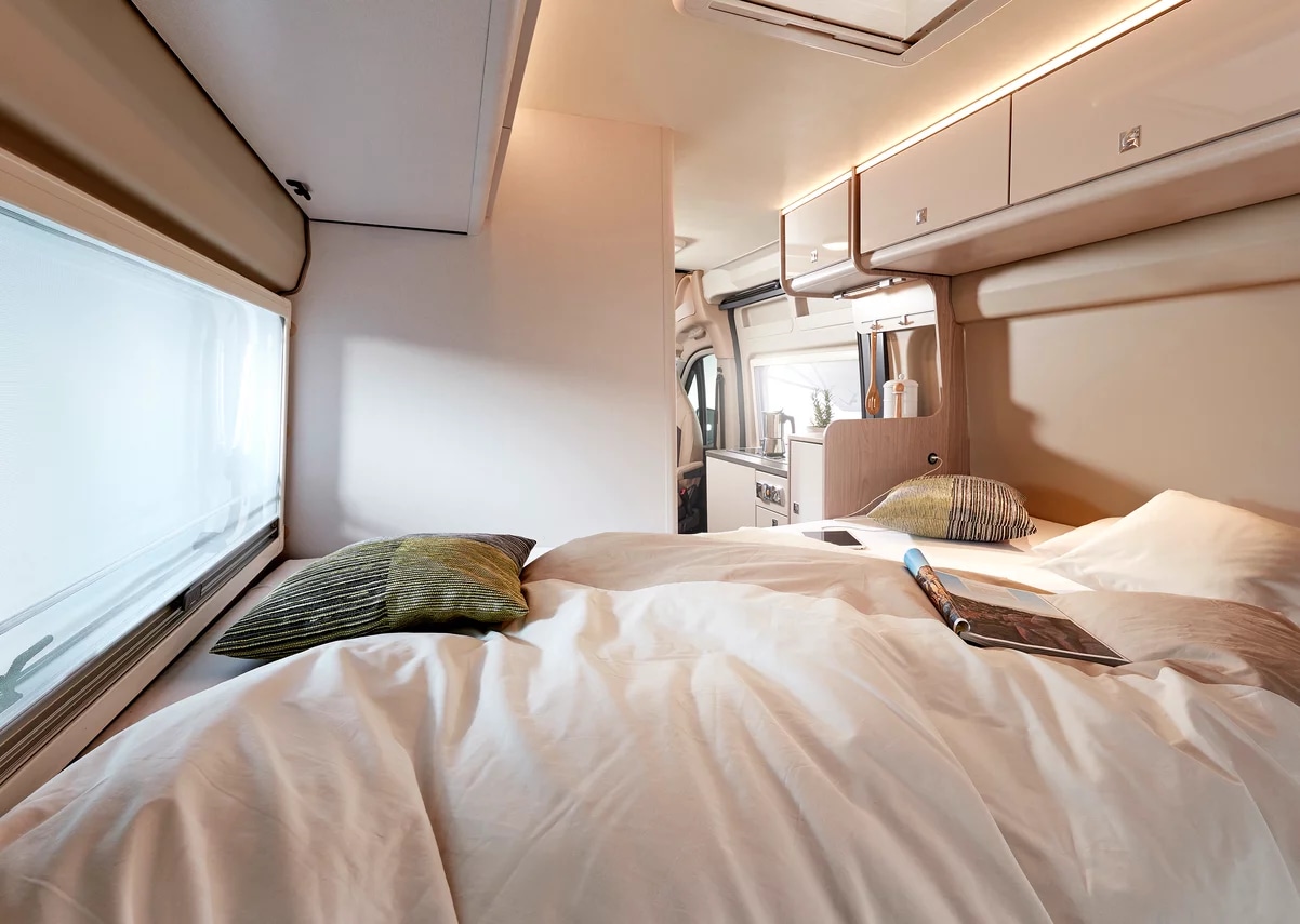 Cozy RV rental bedroom and living area, featuring a comfortable bed, window, and a glimpse of the kitchen. Ideal for travel.. Other BURSTNER CAMPEO C600 2025