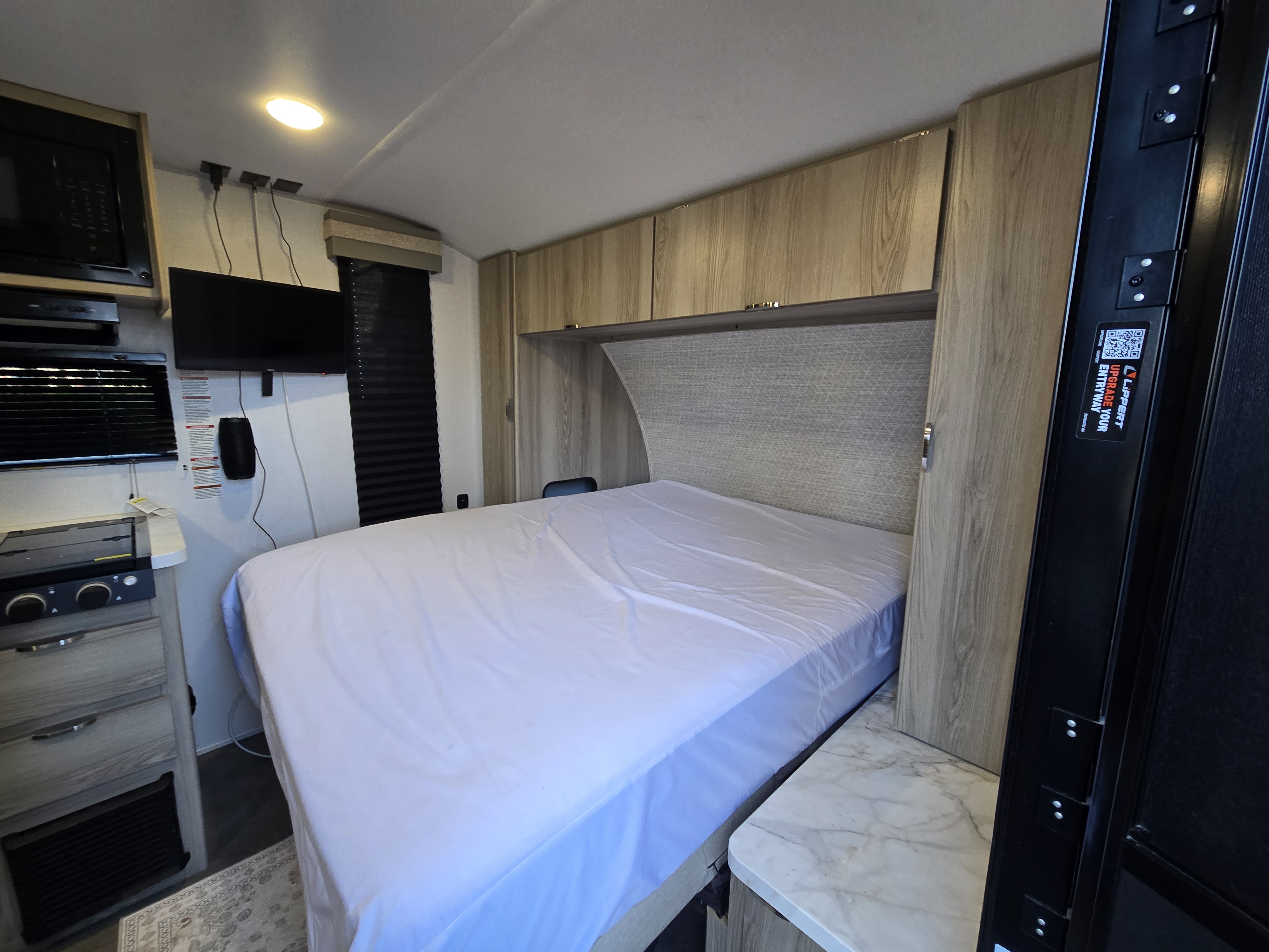 RV rental interior: a bright space featuring a cozy bed, integrated kitchen, TV, and overhead storage for comfortable travels.. Forest River Wildwood FSX Platinum 2024
