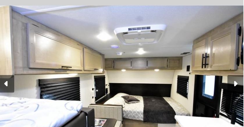 Comfortable RV rental bedroom with an inviting bed, ample overhead cabinets, windows with blinds, and a ceiling AC unit.. Forest River Wolf pup Black Label 16BHSBL 2026