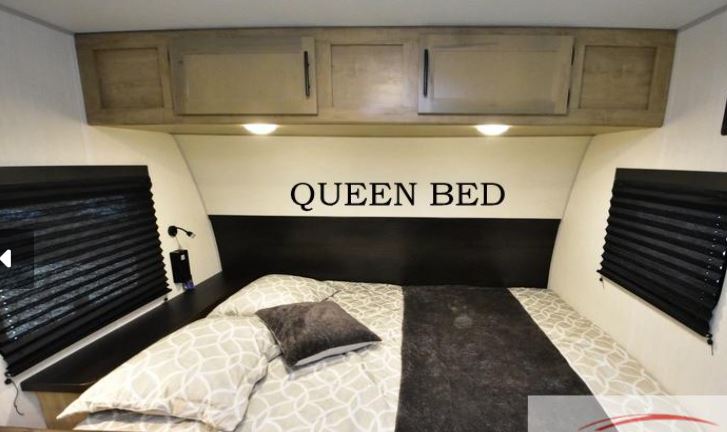 Comfortable queen bed in this rv rental bedroom with overhead cabinets and windows, perfect for a cozy night's sleep.. Forest River Wolf pup Black Label 16BHSBL 2026