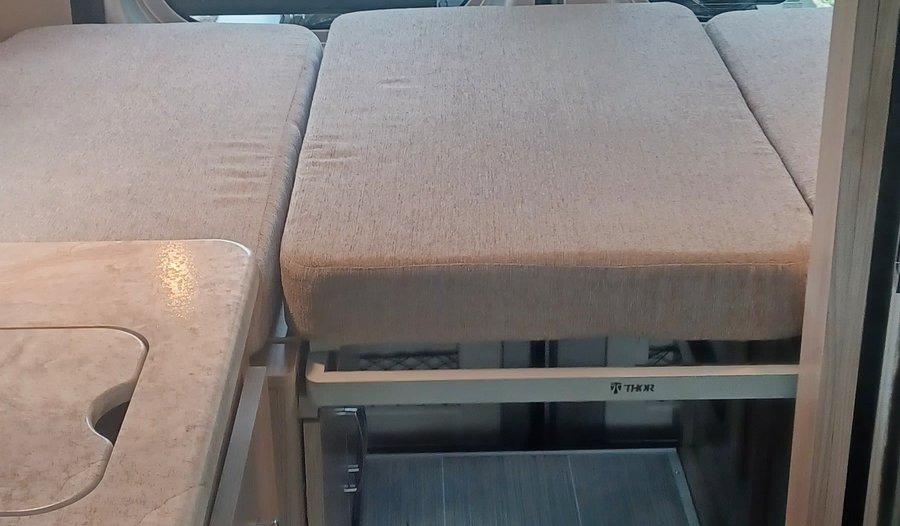 This Thor RV rental interior features a comfortable sleeping area/sofa and a compact kitchen countertop with sink.. Thor Scope 2023