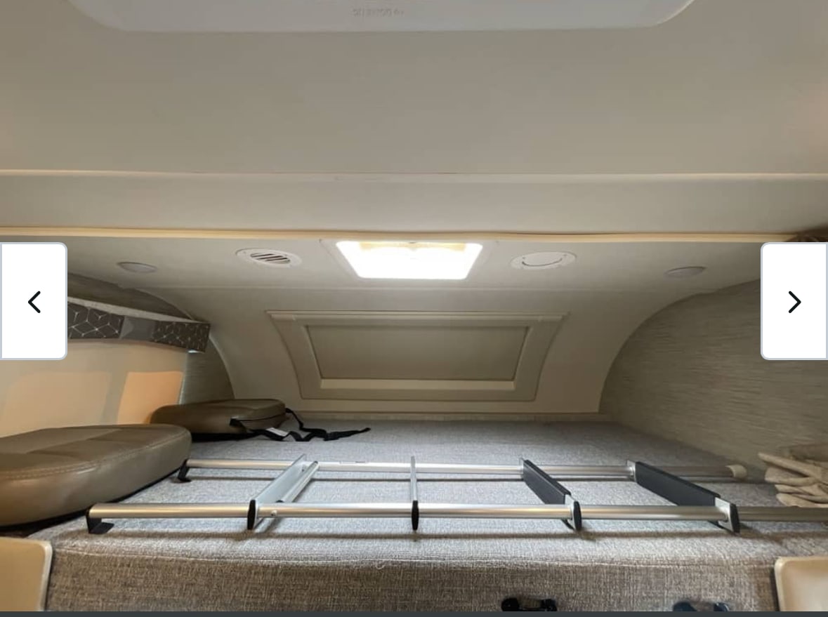RV rental interior: View of a spacious over-cab bunk sleeping area, complete with a ladder and extra cushions on the bed.. Thor Quantum 2021