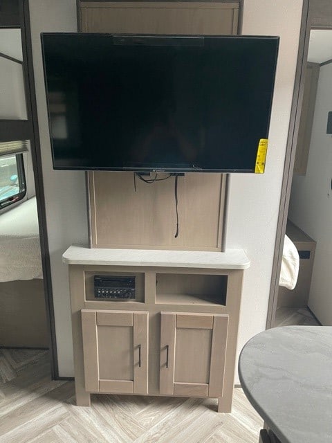 RV rental entertainment center: a flat-screen TV mounted above a cabinet with an audio receiver and storage.. Cruiser RV Shadow Cruiser 2021