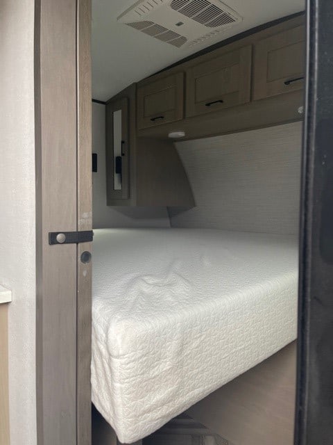 This RV rental bedroom offers a comfortable white mattress, ample overhead storage, and a ceiling AC unit.. Cruiser RV Shadow Cruiser 2021