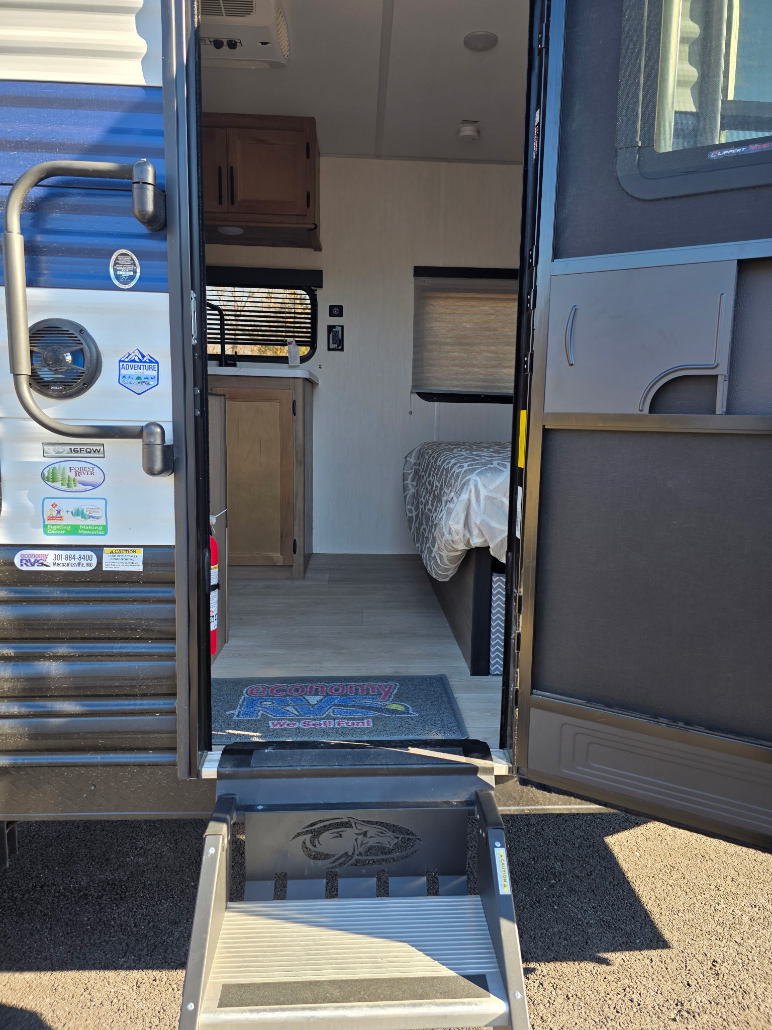 Inside a spacious travel trailer RV rental, featuring an inviting entrance, compact kitchen, and comfortable bed for your journey.. Forest River Cherokee Wolf Pup 2025