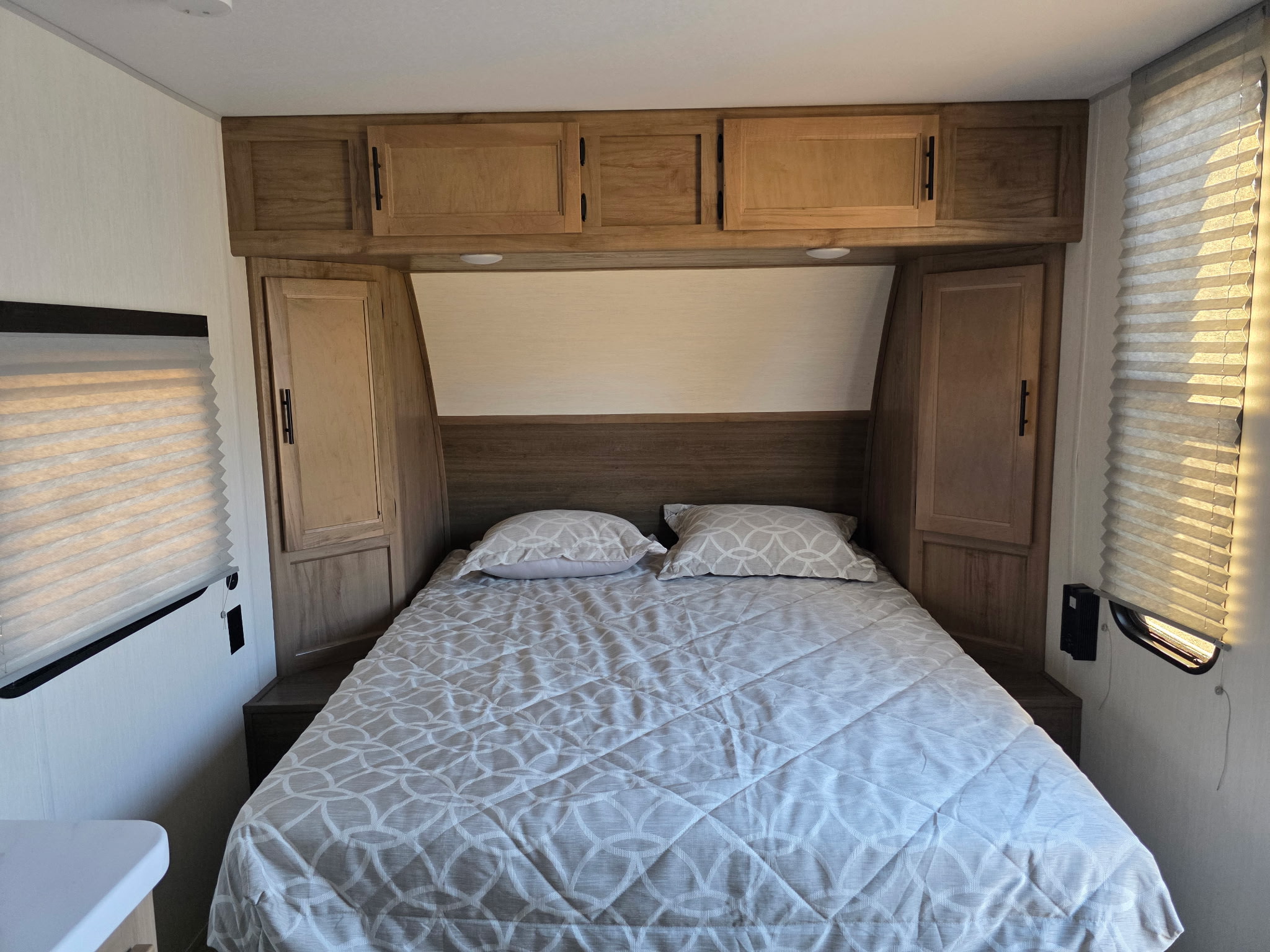 RV rental's cozy bedroom. This compact space includes a patterned bed, wood cabinets, and window blinds.. Forest River Cherokee Wolf Pup 2025