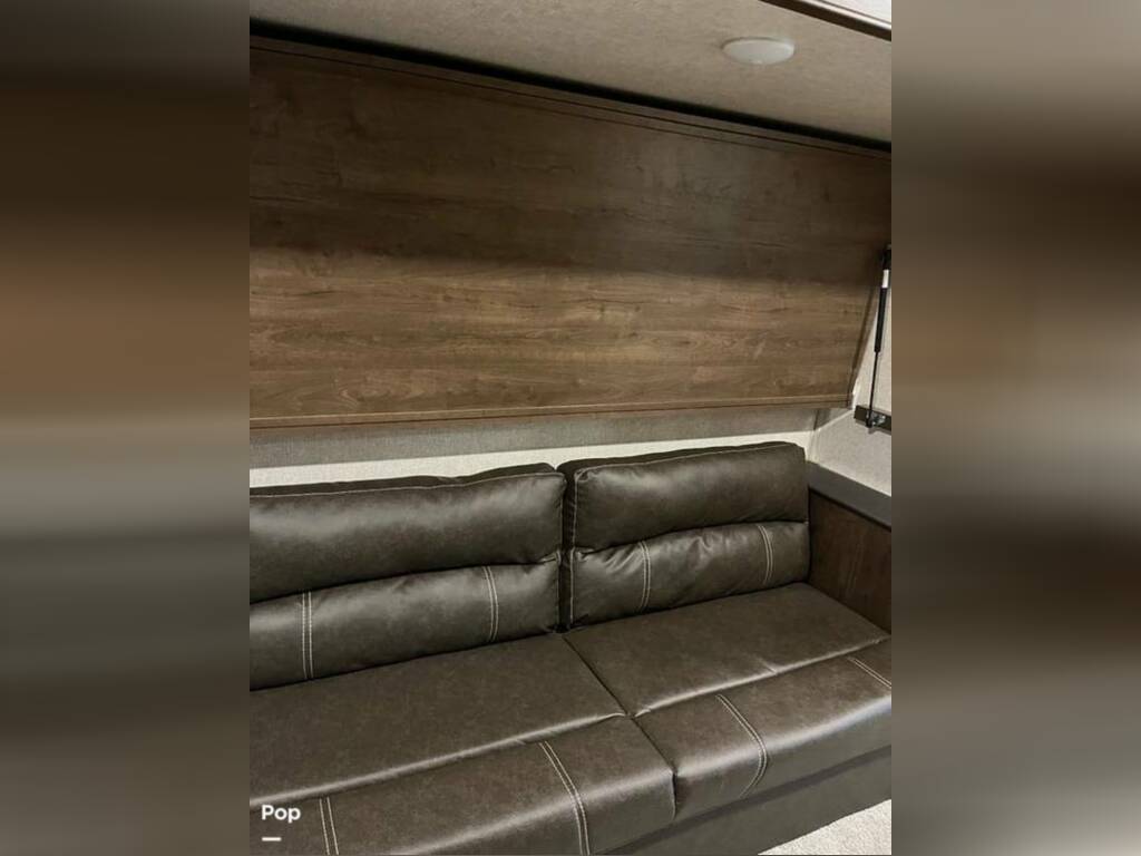 RV rental interior: Comfortable brown sofa below a wall-mounted murphy bed, ideal for a flexible living space.. Keystone RV Cougar 2021