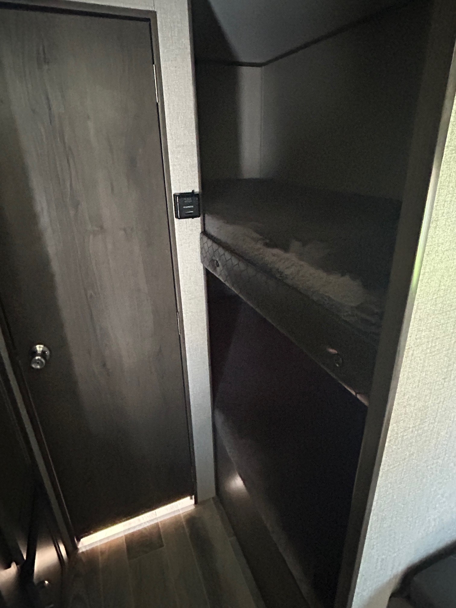 RV rental interior: door, thermostat, and dark bunk beds. Compact sleeping area in a travel trailer.. Jayco Jay Flight SLX 2021