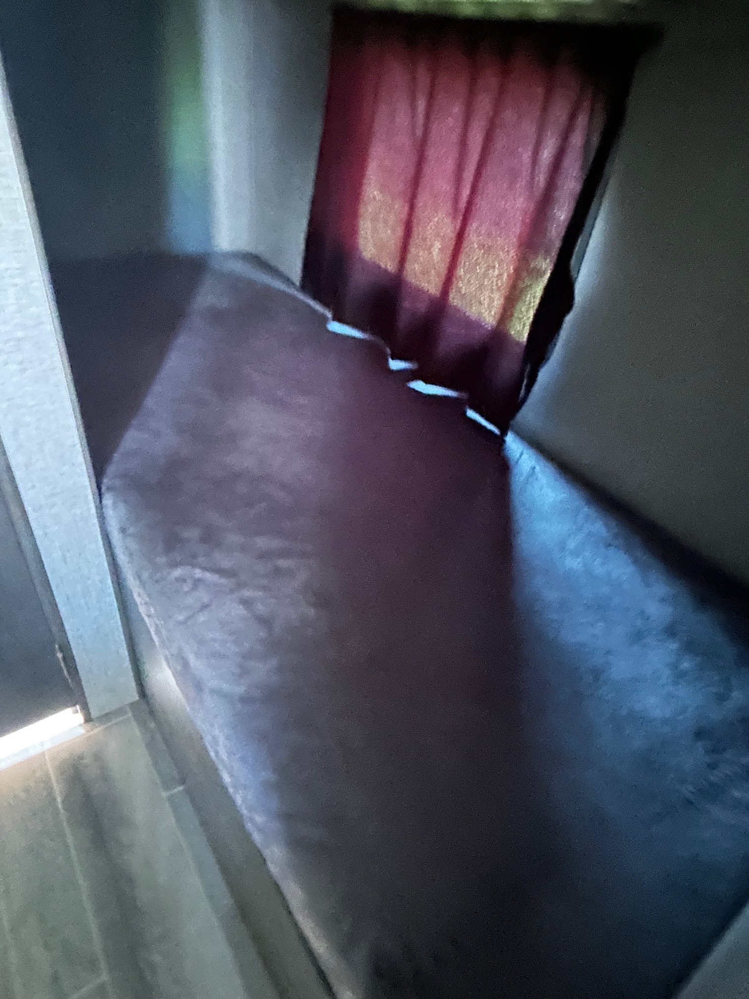 A dark-covered narrow bed or bunk with a window and a deep red curtain, providing compact sleeping in an RV rental.. Jayco Jay Flight SLX 2021