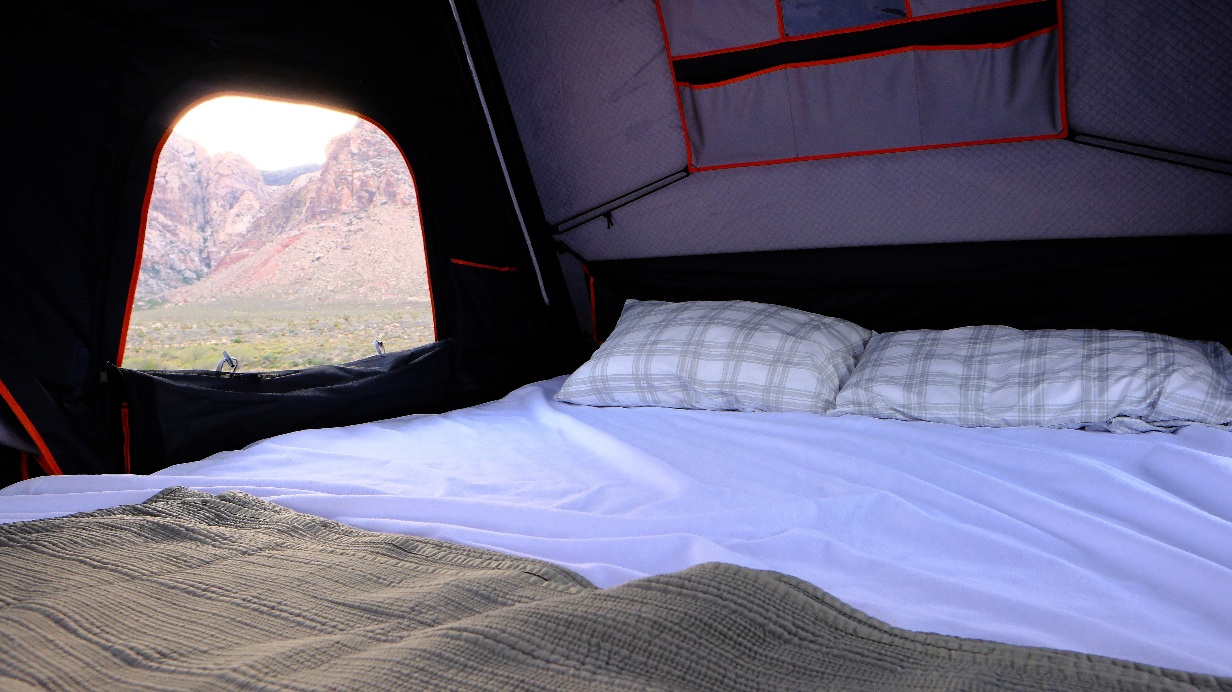 Comfy rv rental bed inside a rooftop tent with a stunning desert mountain view, perfect for camping.. Ford Roofnest 2024