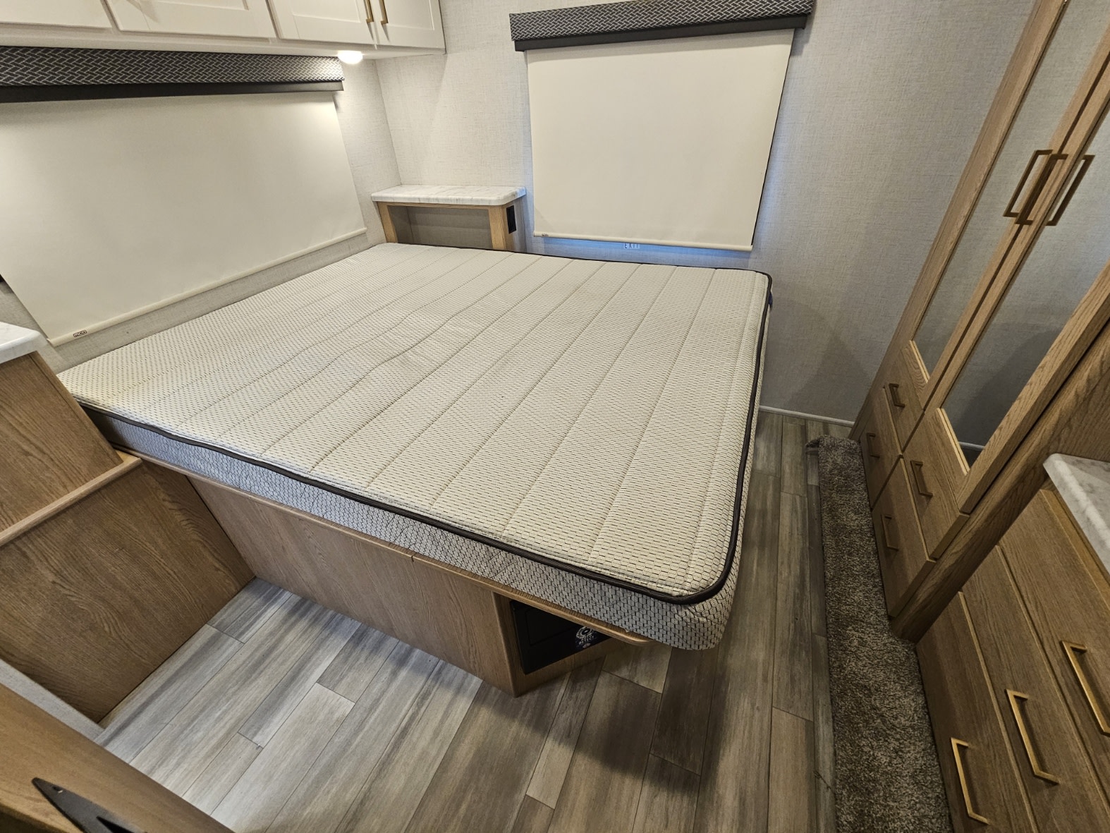 Spacious RV rental bedroom featuring a large bed, nightstands, overhead cabinets, and a mirrored wardrobe.. Thor Motor Coach FourWinds 2026