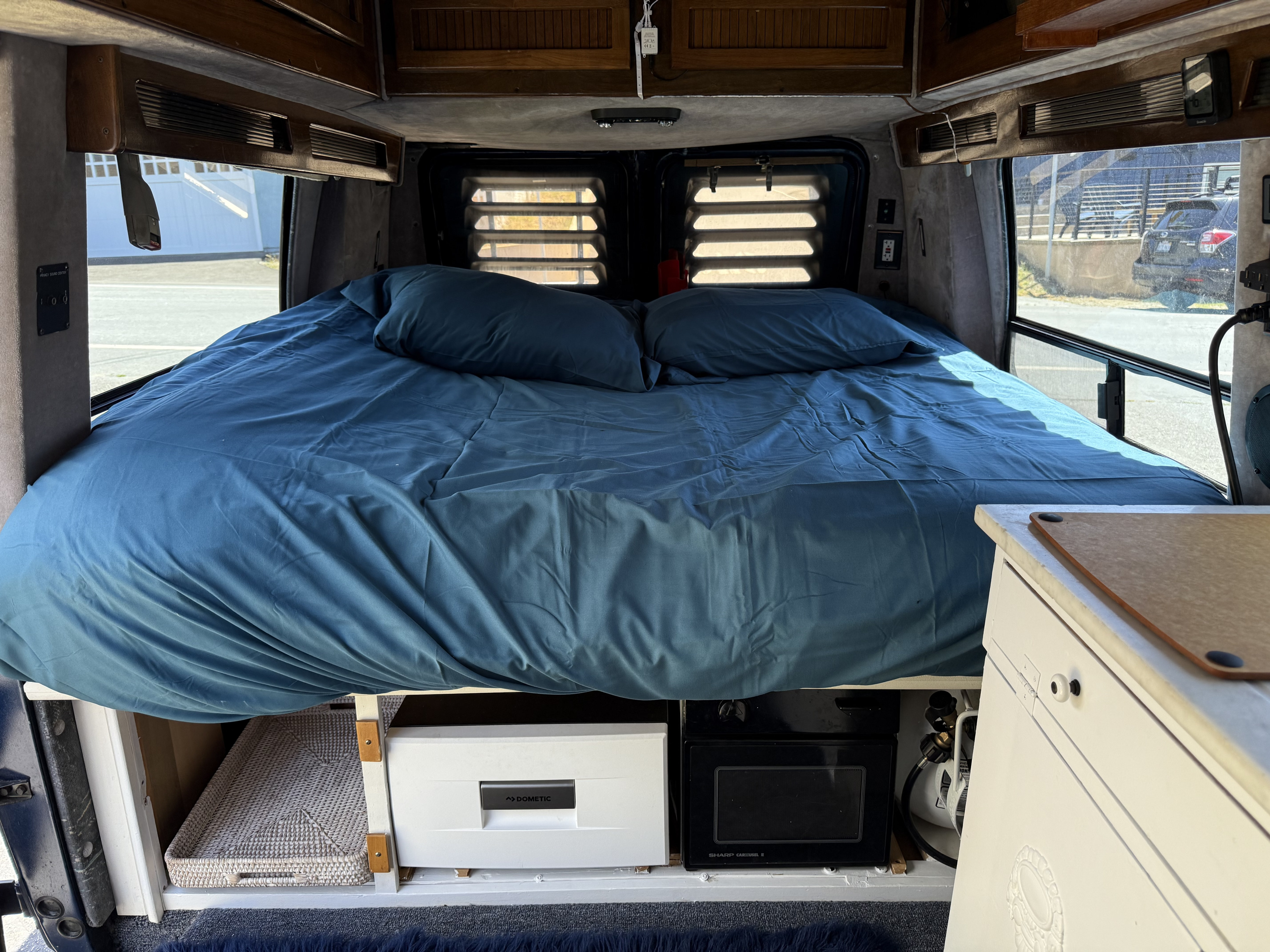 This RV rental offers a comfortable blue bed with under-bed storage, including a Dometic fridge and Sharp microwave.. Gmc Sportsmobile 1995