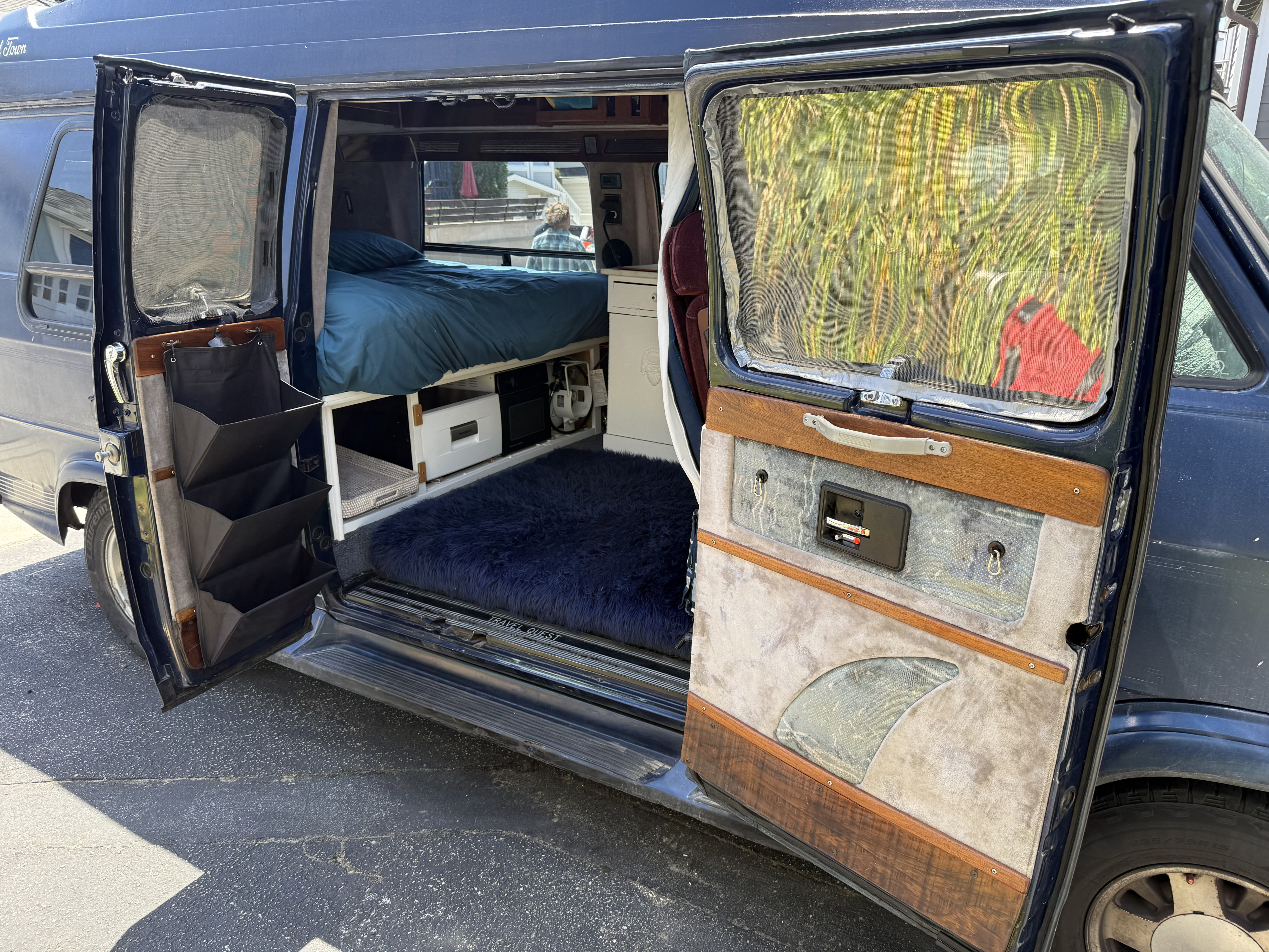 Step into adventure! This RV rental showcases its cozy, custom interior with a bed, smart storage, and a fluffy rug.. Gmc Sportsmobile 1995