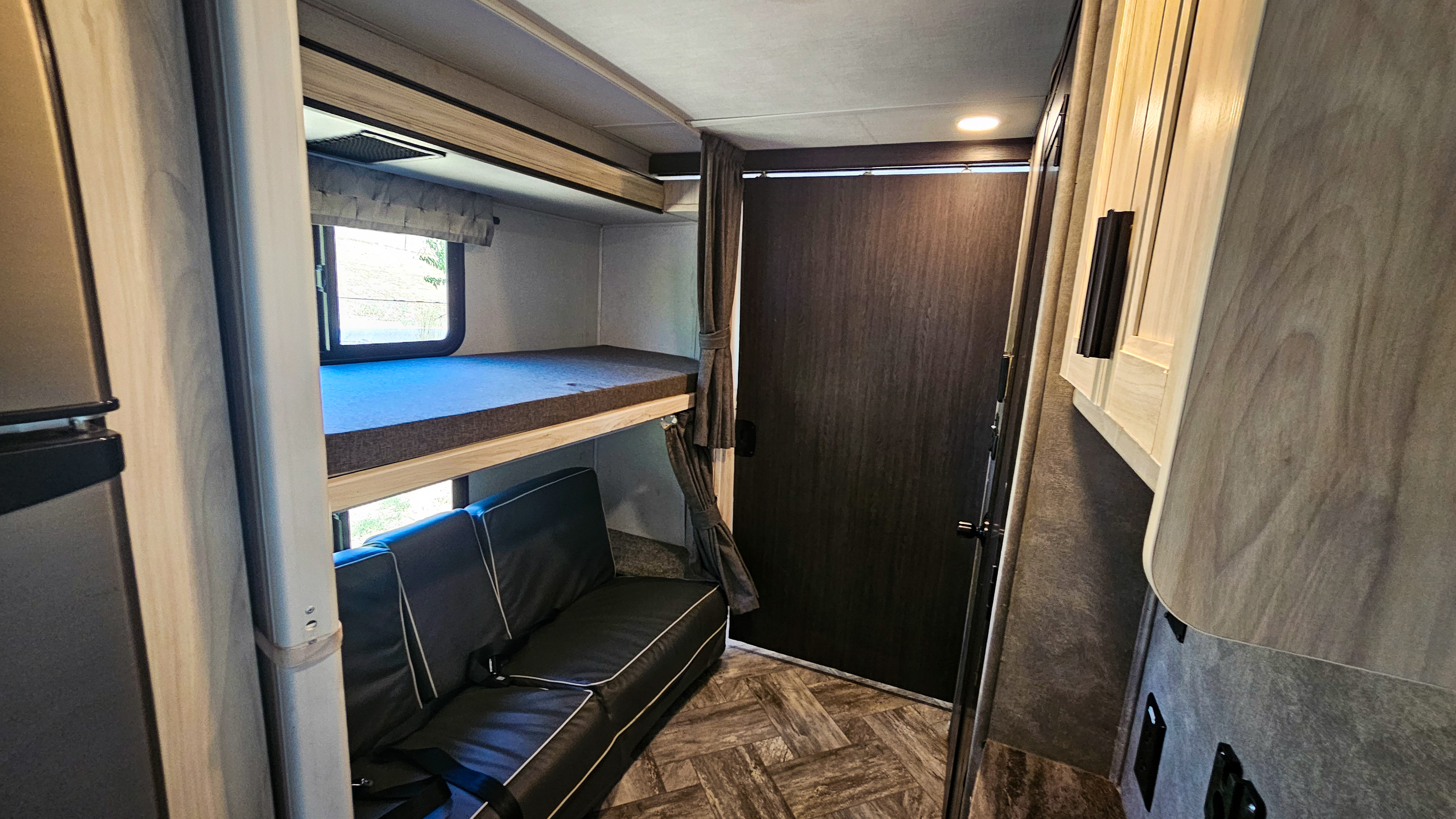 RV rental interior: cozy bunk beds with a convertible sofa, privacy panel, and storage cabinets.. Forest River Sunseeker LE 2022