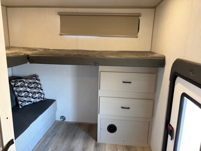 Compact RV rental sleeping area with bunk beds, built-in storage drawers, and a lower bench seat for comfortable travel.. Forest River Wildwood 2023