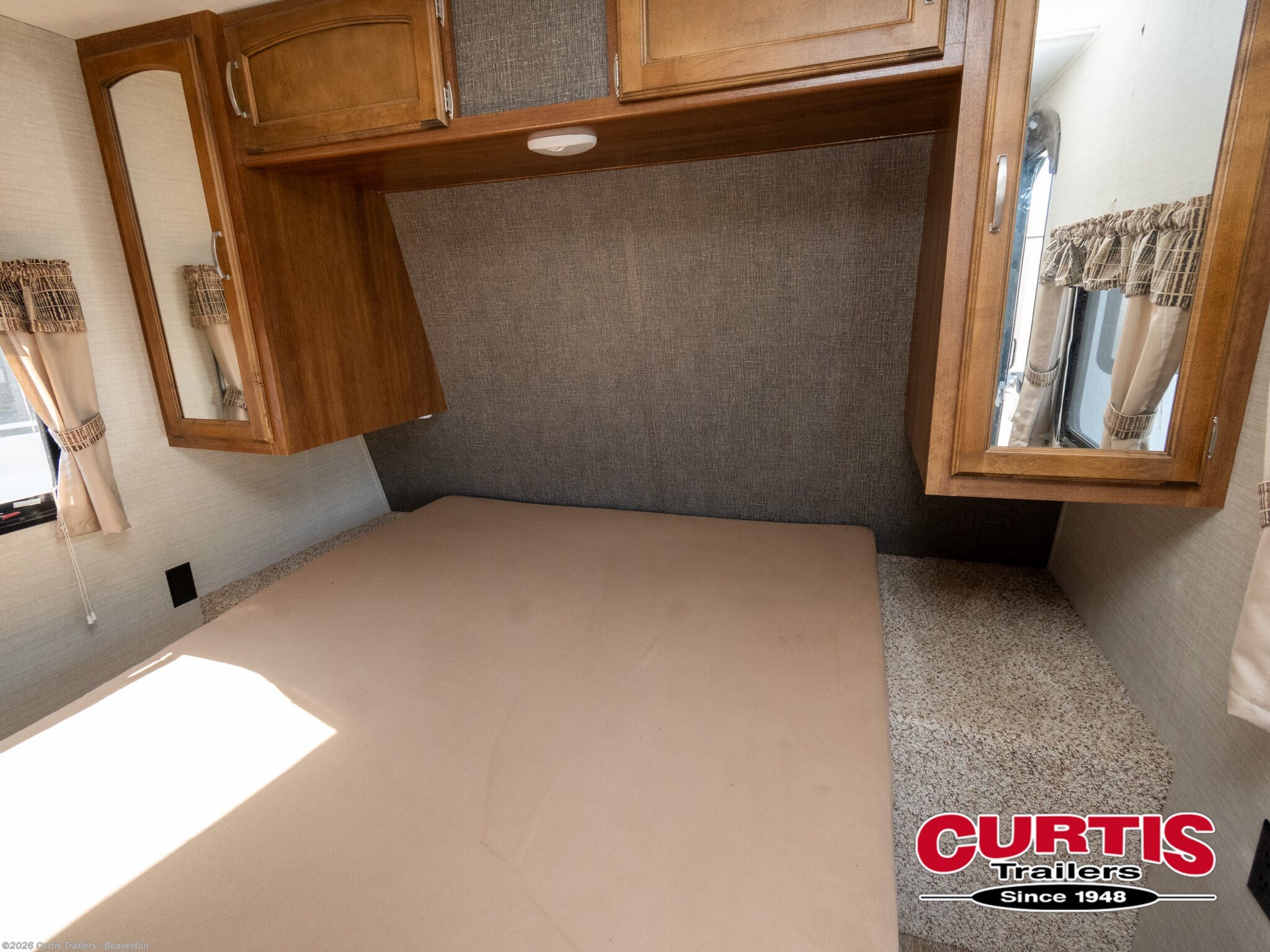 Explore this RV rental's cozy bedroom featuring a comfortable bed, overhead cabinets with mirrors, and ample storage.. Springdale sm2820bh16 2016