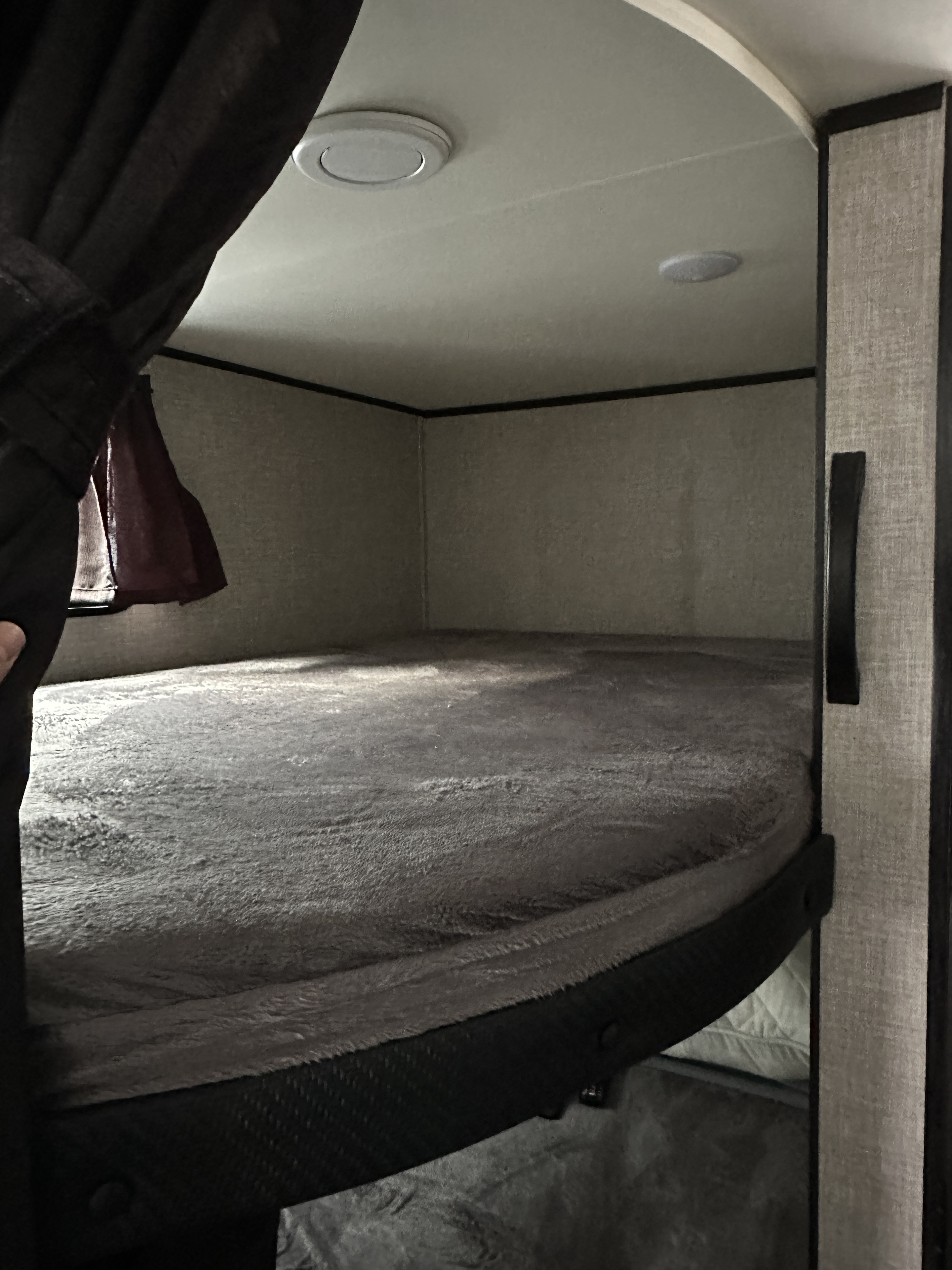 Cozy RV rental bunk bed with a soft grey blanket, dark curtain, and ceiling lights, perfect for sleeping.. Jayco Jay Flight SLX 2022