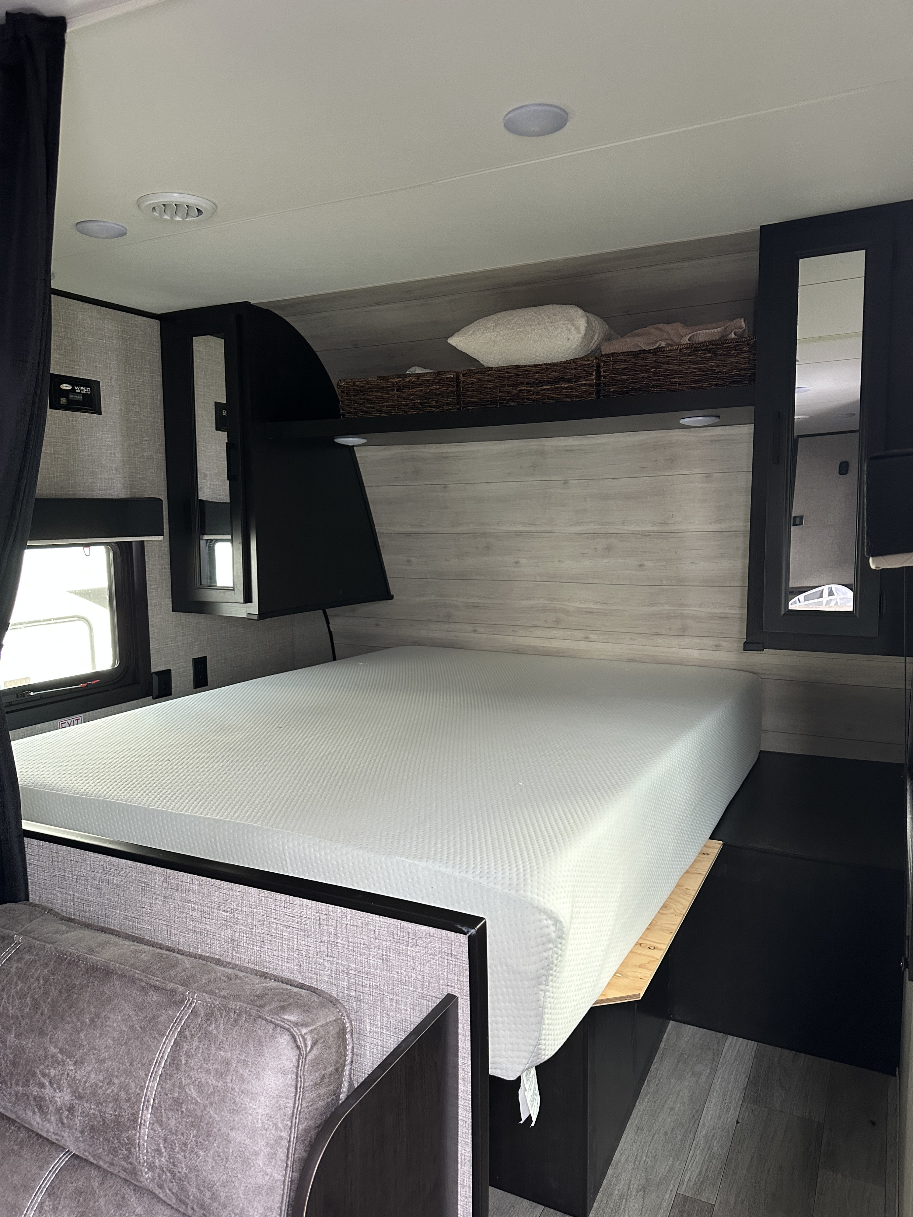RV rental bedroom with a white mattress, overhead cabinets, and modern wood-paneled walls, perfect for travel.. Jayco Jay Flight SLX 2022
