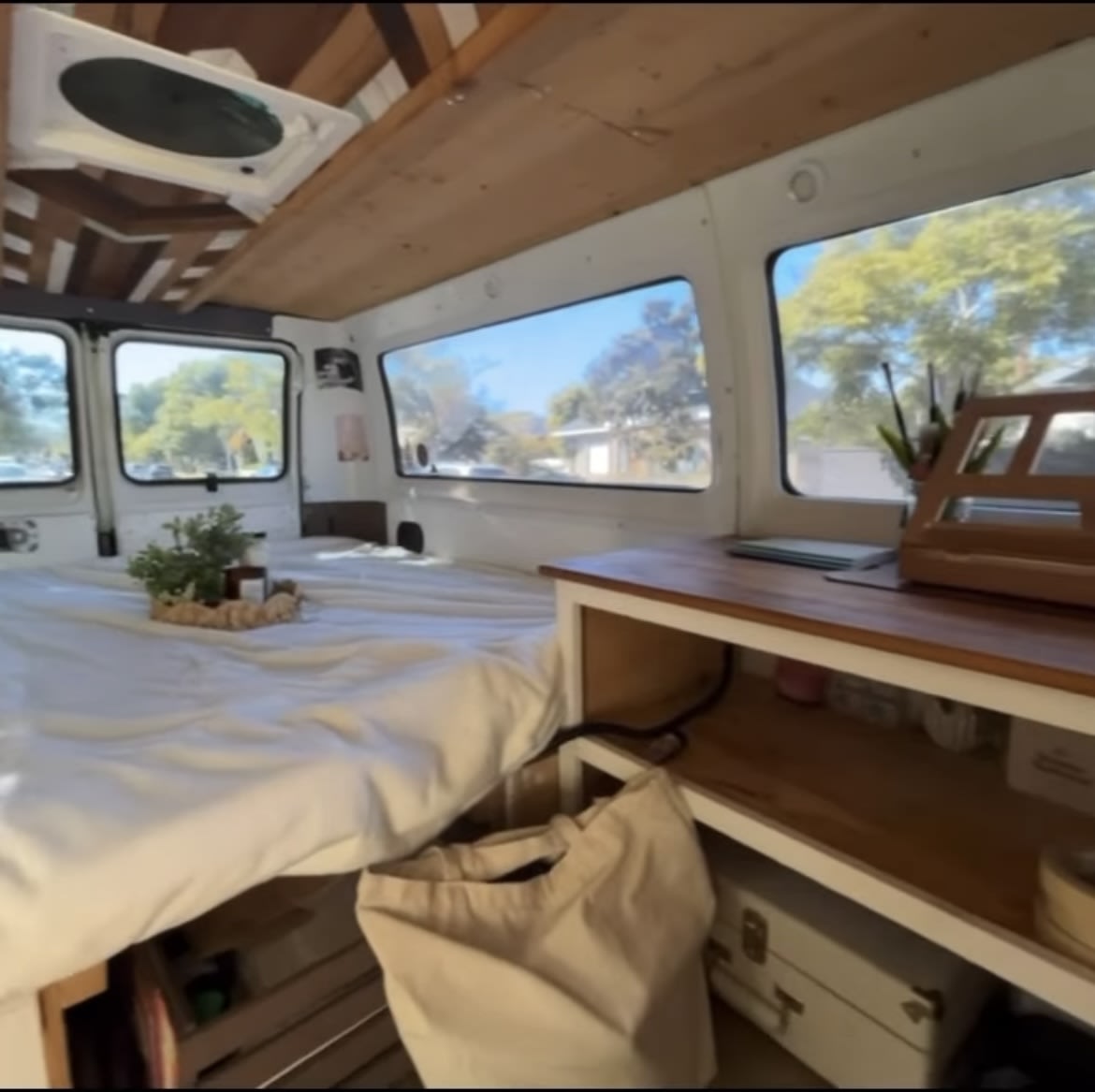 Cozy RV rental interior: A bright camper van features a bed, vent, scenic windows, and a wooden desk, perfect for mobile living.. dodge dodge ram van 2001