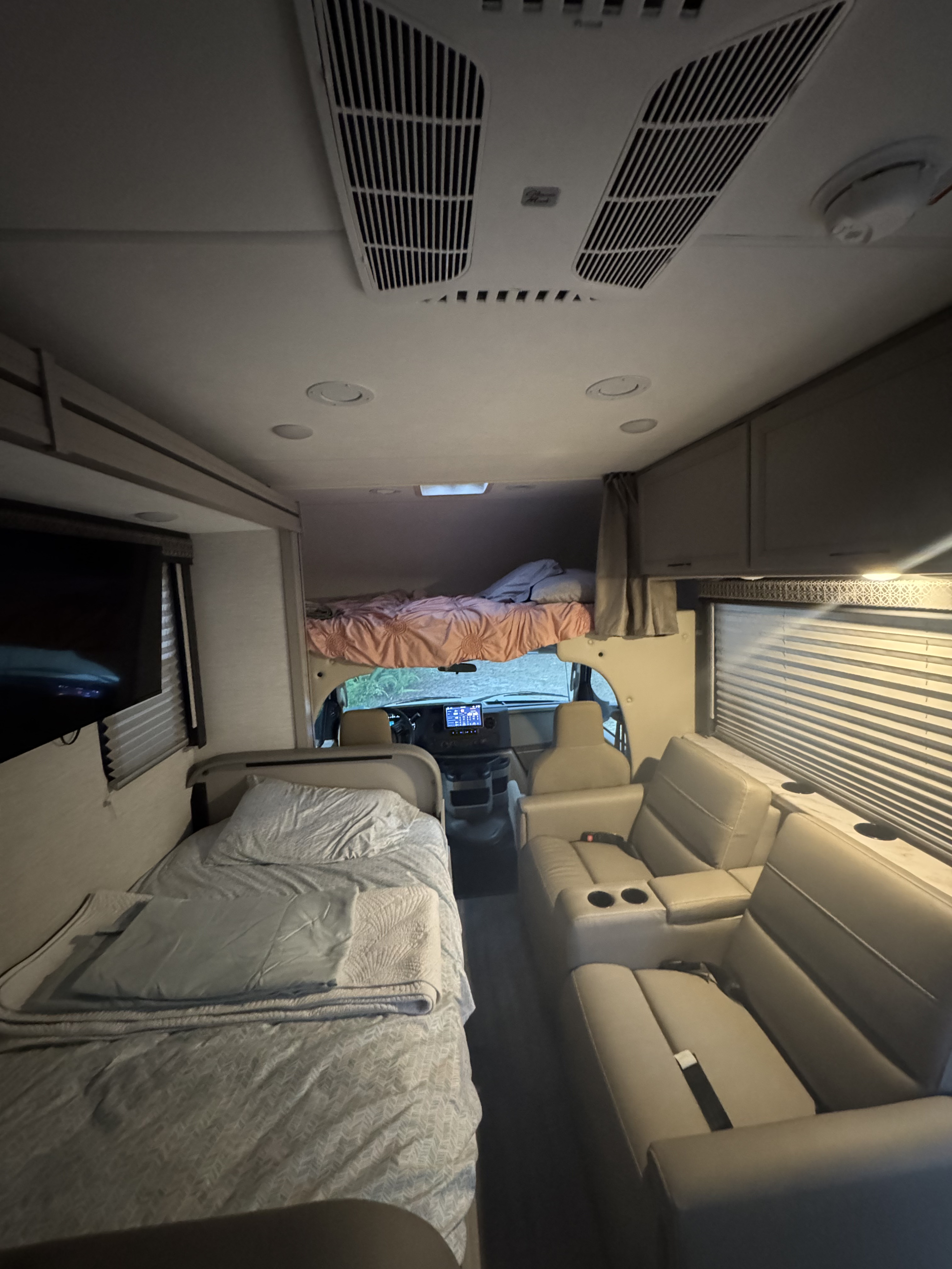 Inside this cozy rv rental: a front cab-over bunk, a bed on the left, and comfortable recliners with cup holders on the right.. Thor Quantum SE 2025