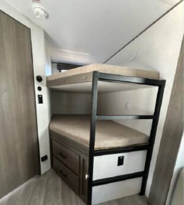 This RV rental features cozy bunk beds with built-in storage drawers, ideal for compact living and sleeping arrangements.. Grand Design Transcend Xplor 2026