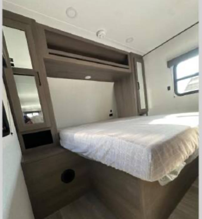 RV rental bedroom: cozy space with bed, overhead storage, mirrored wardrobes, and a window for natural light.. Grand Design Transcend Xplor 2026