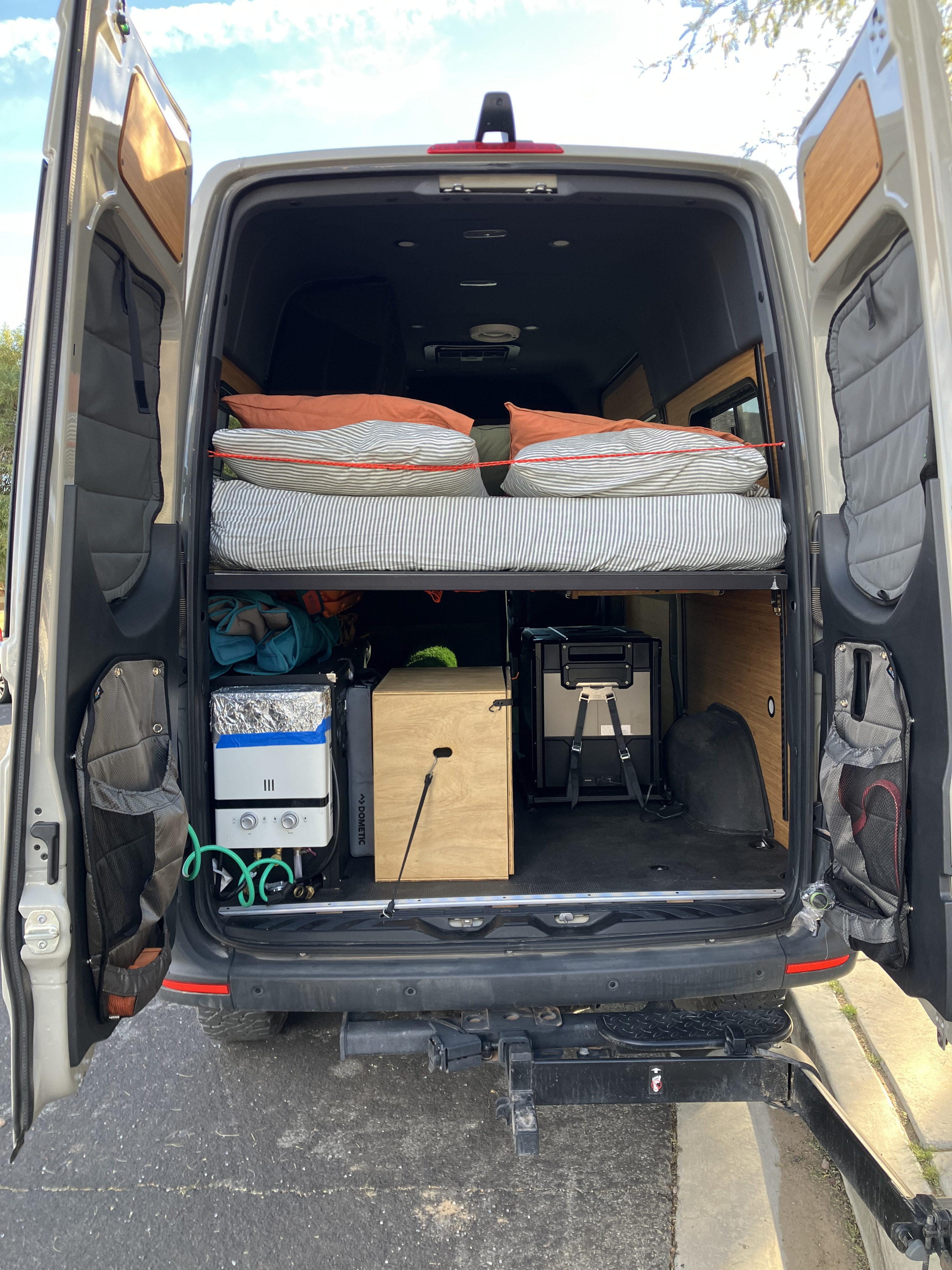 RV rental with custom camper van conversion, featuring a raised bed, Dometic fridge, and portable shower for adventure.. Mercedes Sprinter 2024