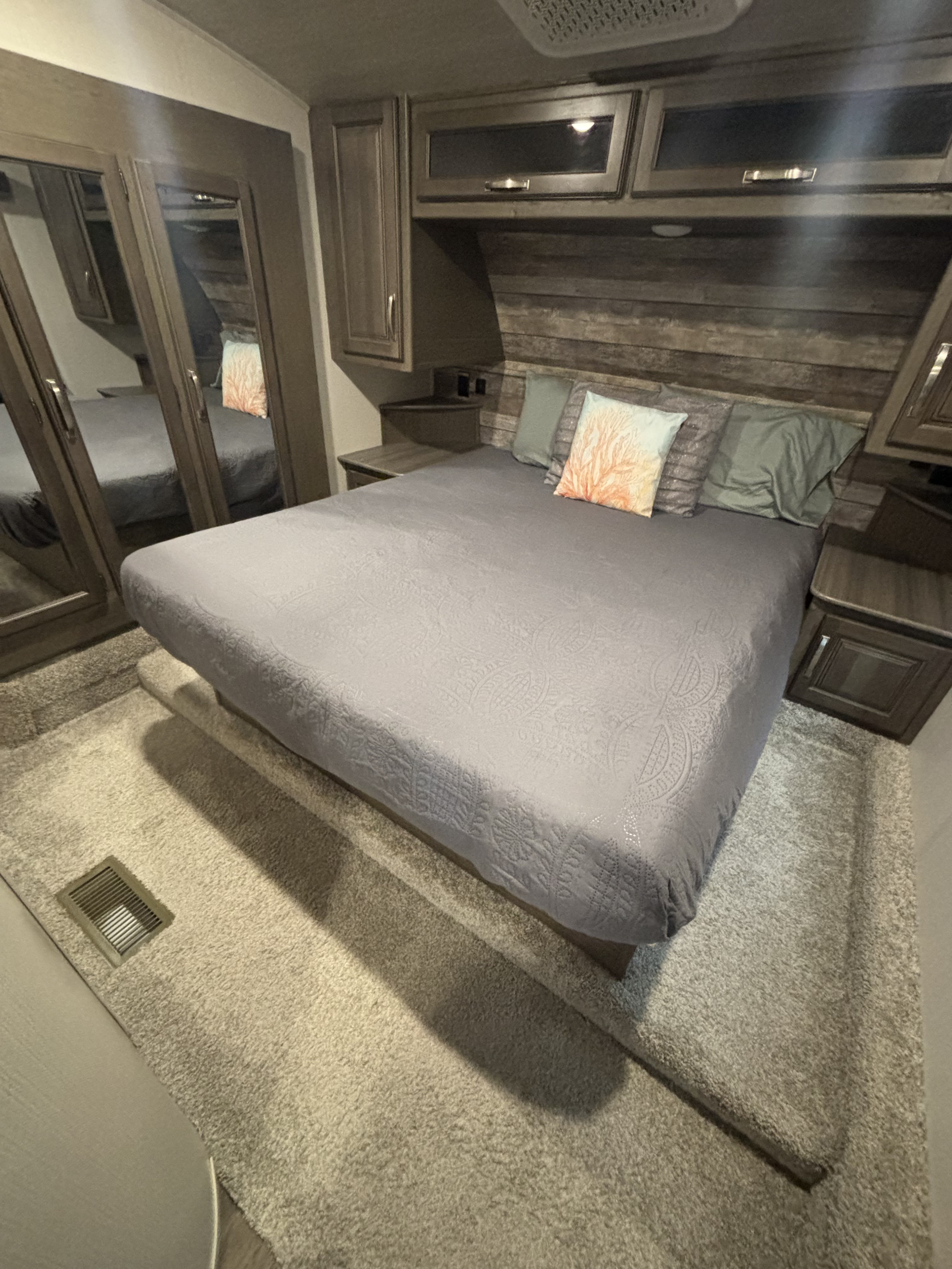 Step into comfort! This RV rental bedroom features a cozy bed, ample storage cabinets, and mirrored closet doors.. Keystone Cougar 2022