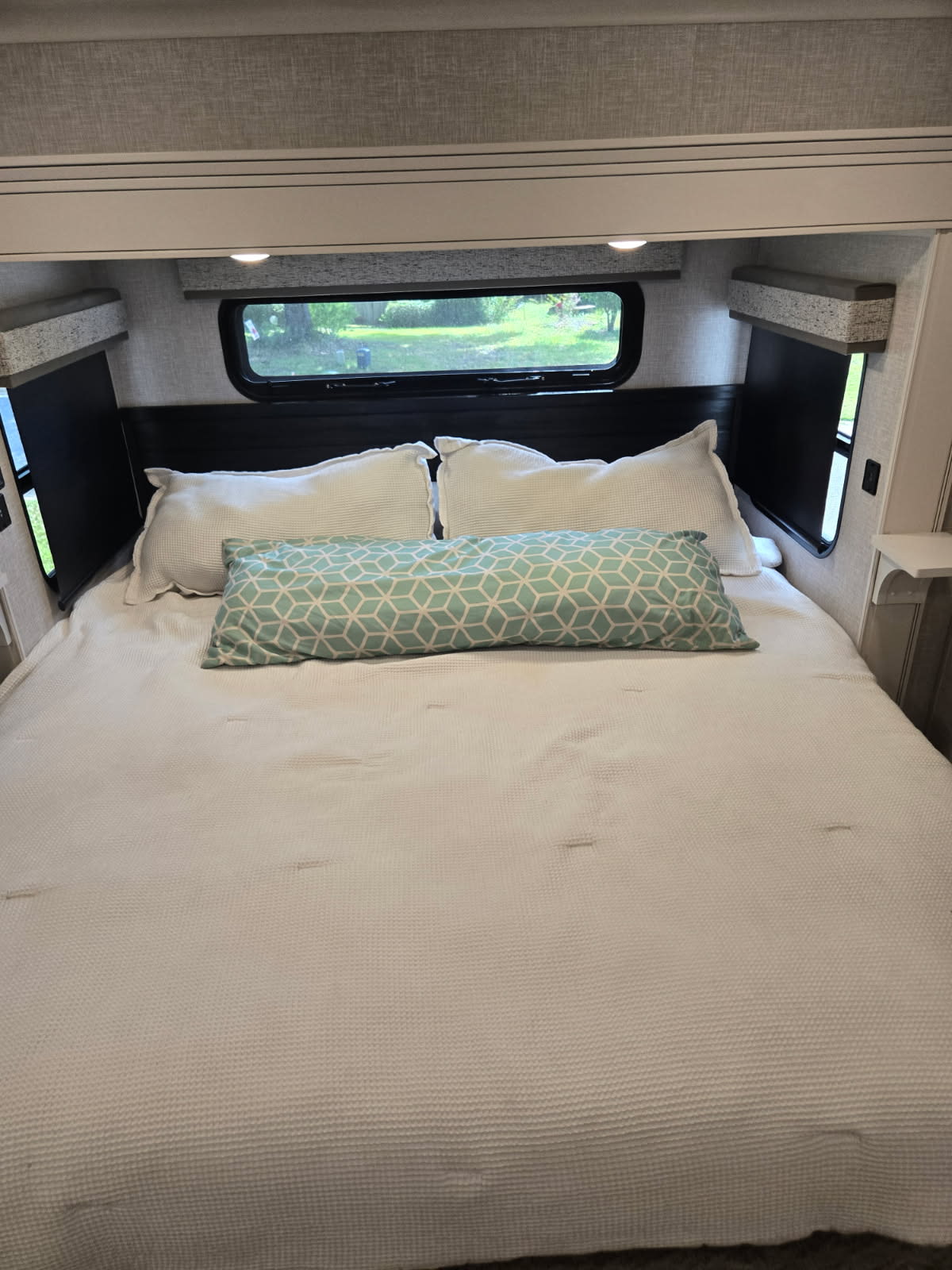 RV rental bedroom: a comfortable white bed, turquoise pillow, and window view.. Jayco North Point 2024