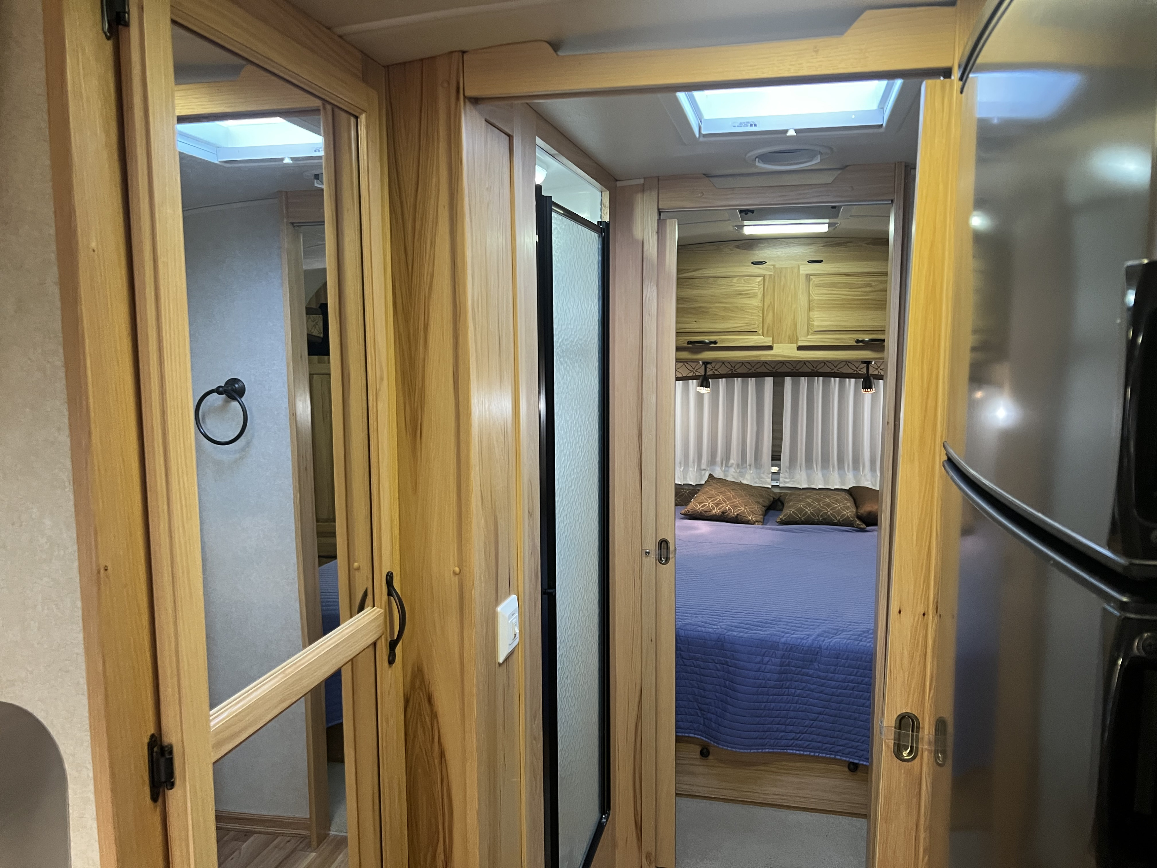 Bright and airy RV rental interior, showing the bedroom, shower stall, and a glimpse of the bathroom facilities.. Airstream Classic 2012