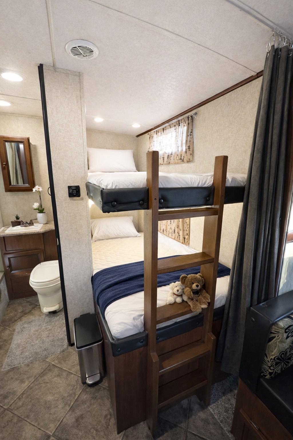 RV rental interior: cozy bunk beds with a ladder for sleeping, and a compact bathroom with a toilet and sink.. Forest River Palomino Solaire 2020