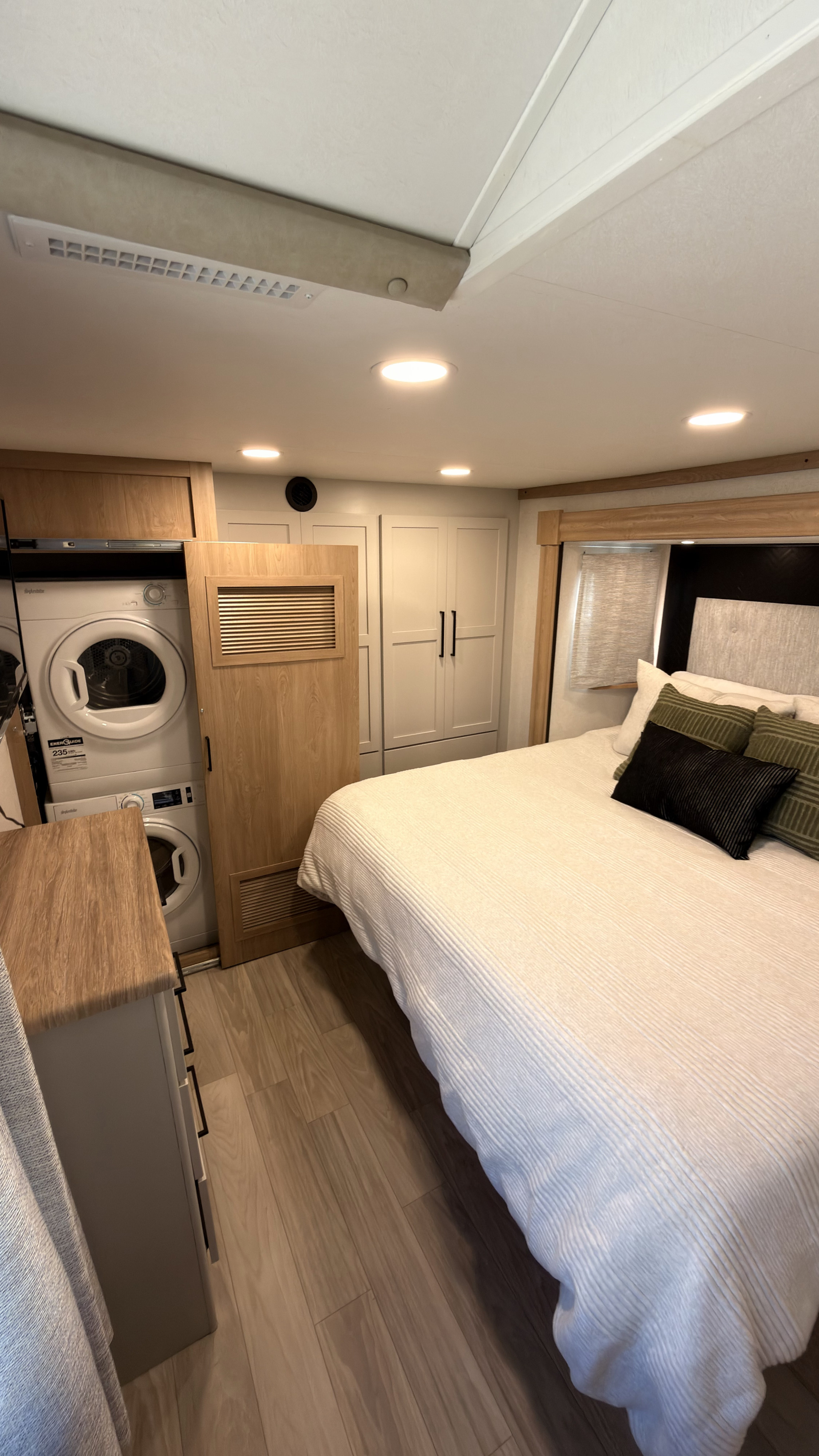 This RV rental bedroom features a cozy bed, stacked washer/dryer, and integrated storage, maximizing compact living.. Forest River Sierra 3990FL 2025