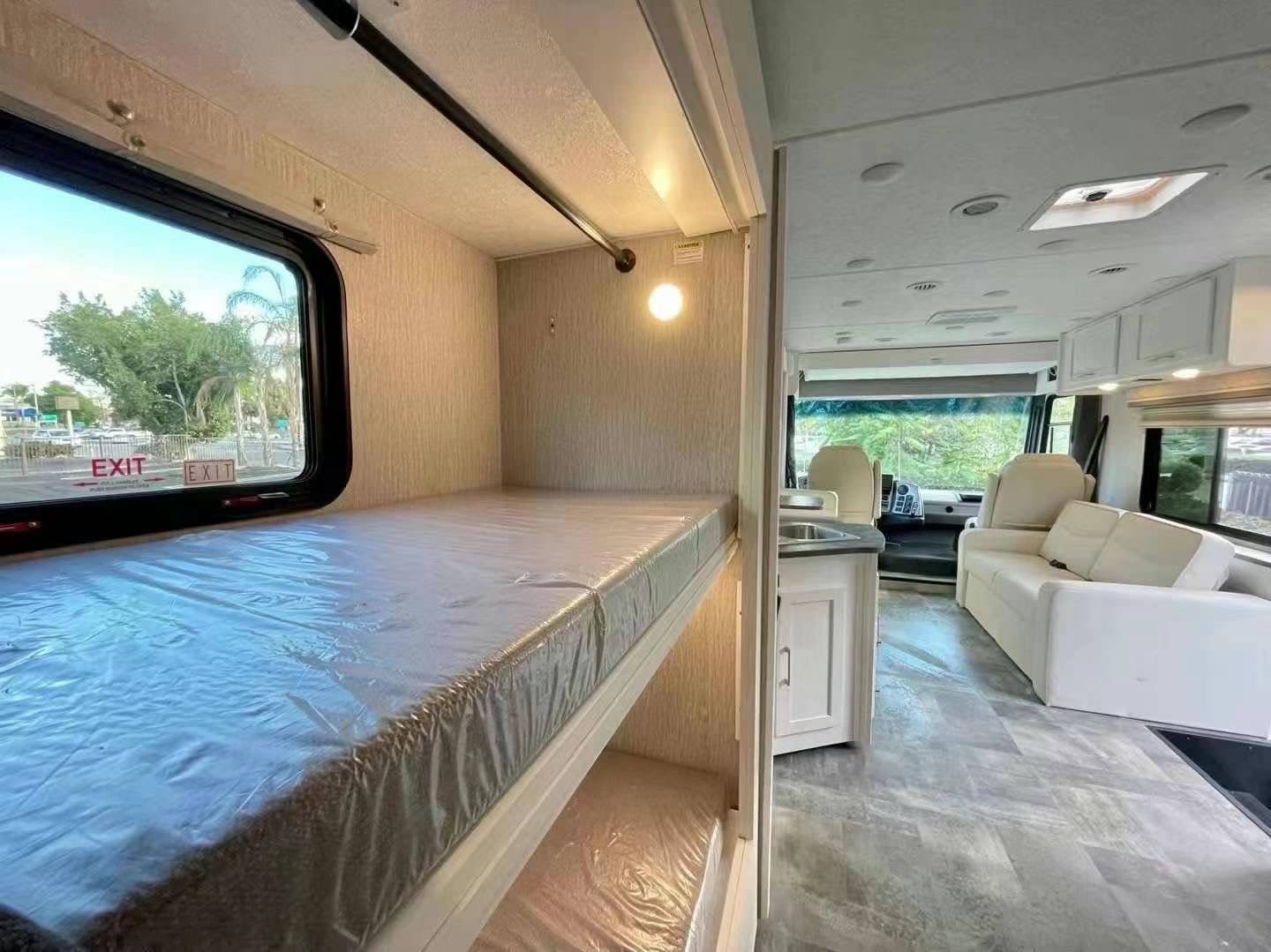 Clean RV rental interior featuring bunk beds, kitchen counter, and a spacious living area with sofa and captain's chairs.. Coachmen Pursuit BH31 2023