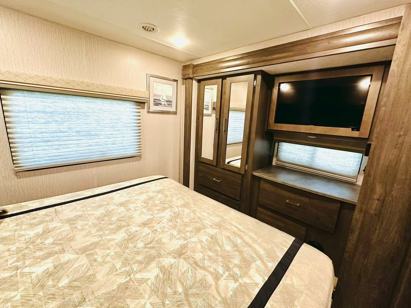 Comfortable RV rental bedroom with a cozy bed, TV, and wardrobe, perfect for relaxing after your adventures.. Coachmen Pursuit 31BH 2023