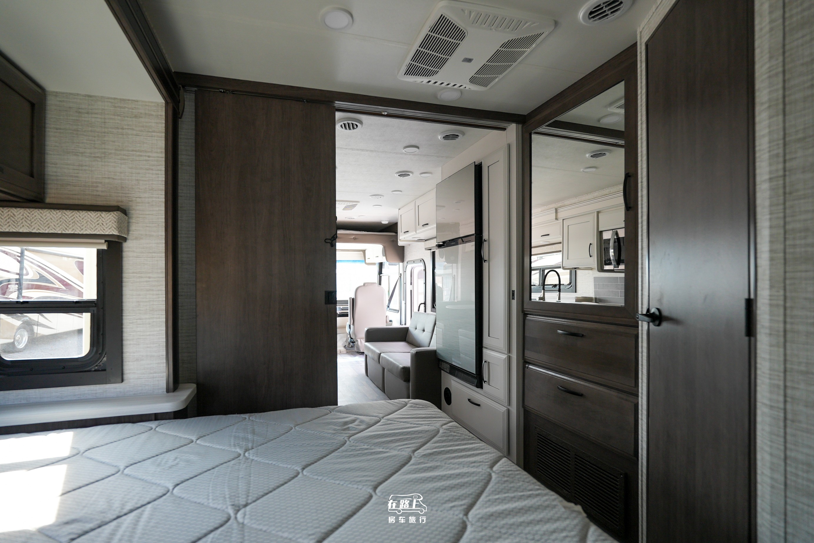Cozy rv rental interior: bedroom with sliding door open to living area, kitchen, and comfy sofa.. Jayco Travel Supreme A Series 27A 2025