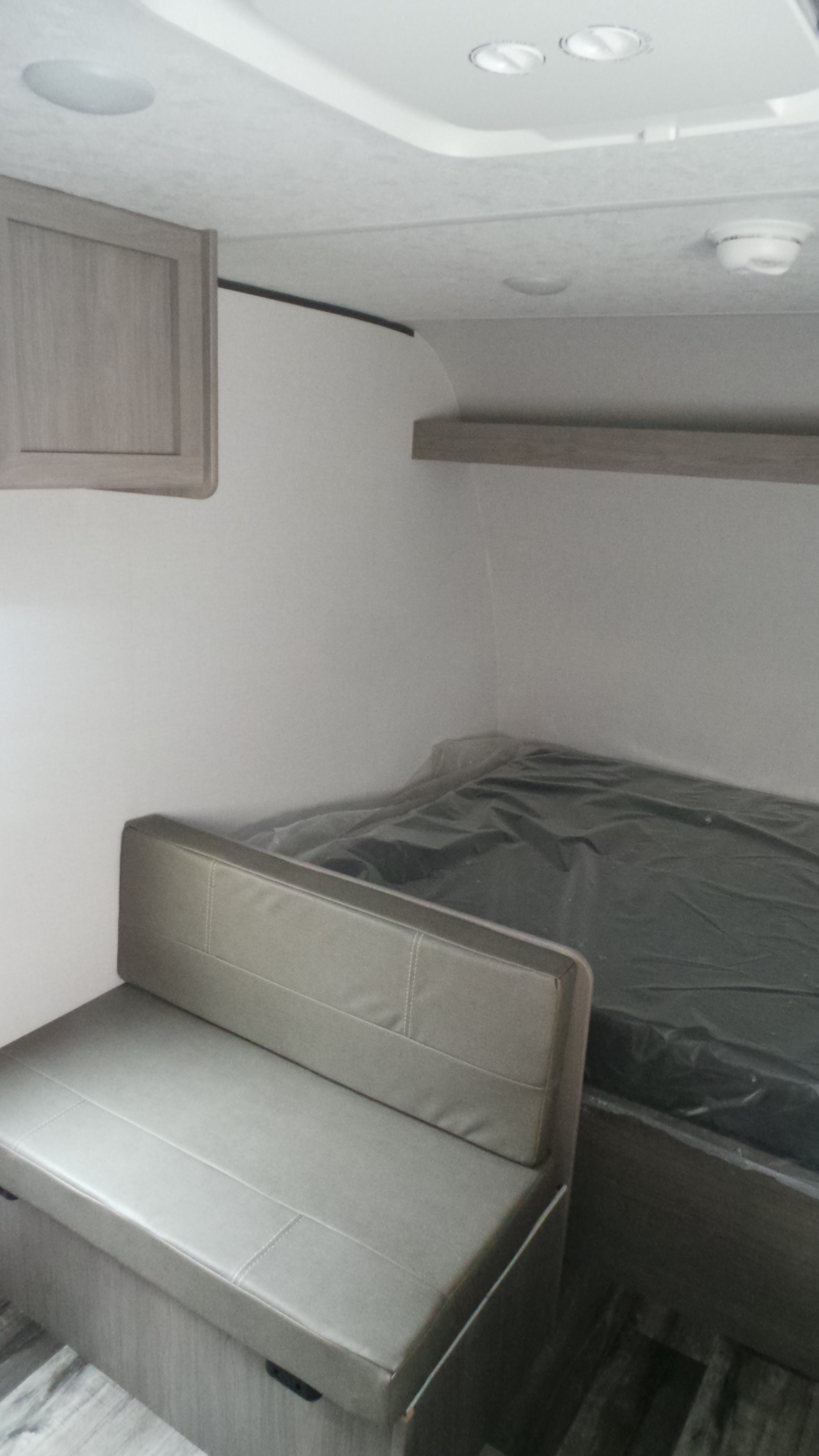 This RV rental interior features a grey dinette, bed covered in plastic, light wood cabinet, and ceiling lights for your comfortable journey.. Colorado Colorado Trailer 2025