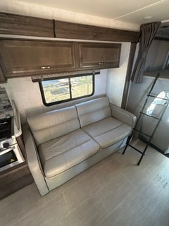 Cozy RV rental interior featuring a sofa, kitchen, window, and ladder to a bunk bed.. Cruiser RV MPG Ultra Lite 2021