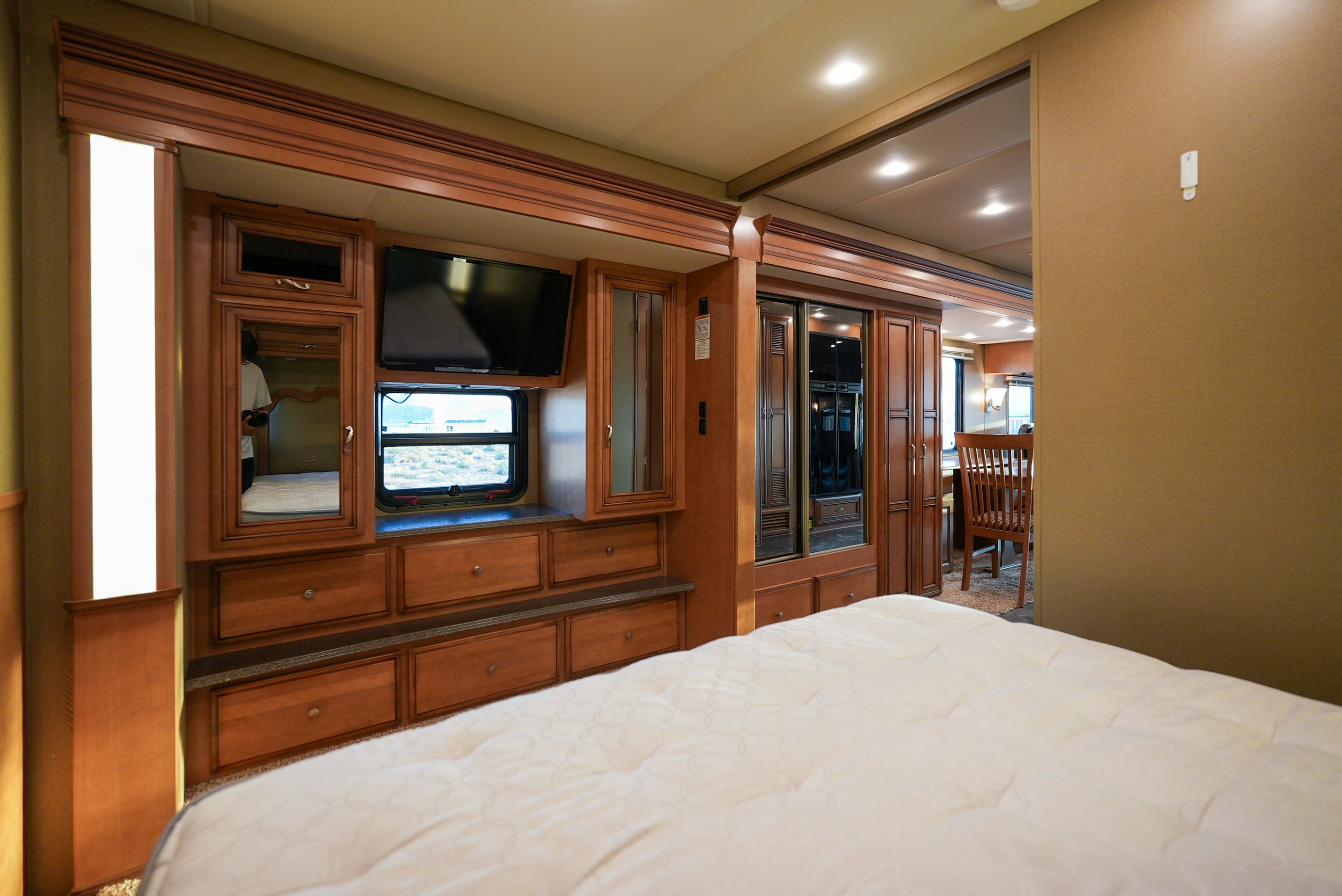 Spacious RV rental bedroom featuring a comfy bed, TV, rich wooden cabinets, and an inviting view to the main living area.. Newmar Canyon Star 3424 2014