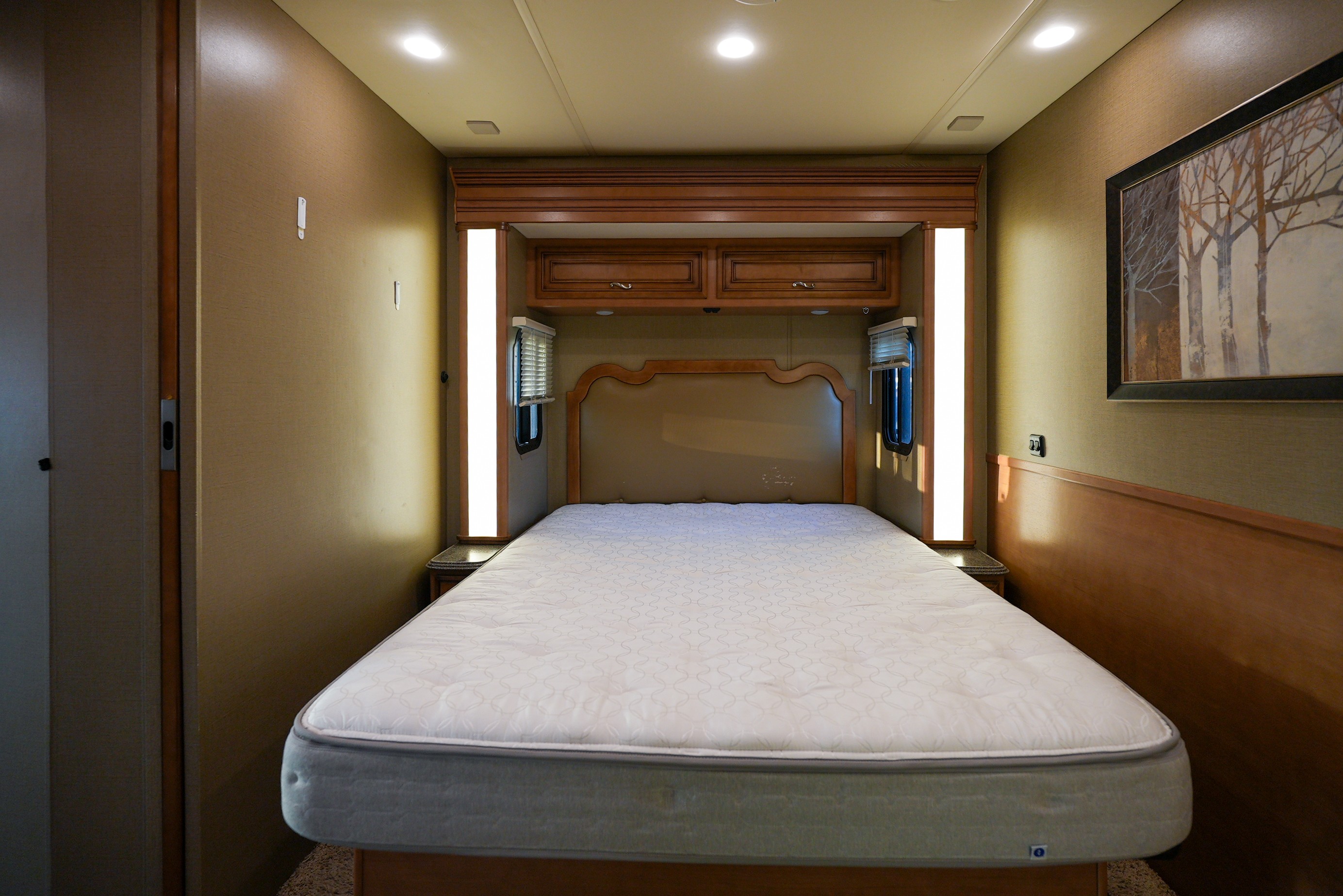 Interior view of an RV rental bedroom featuring a queen bed, built-in storage, and ambient lighting.. Newmar Canyon Star 3424 2014