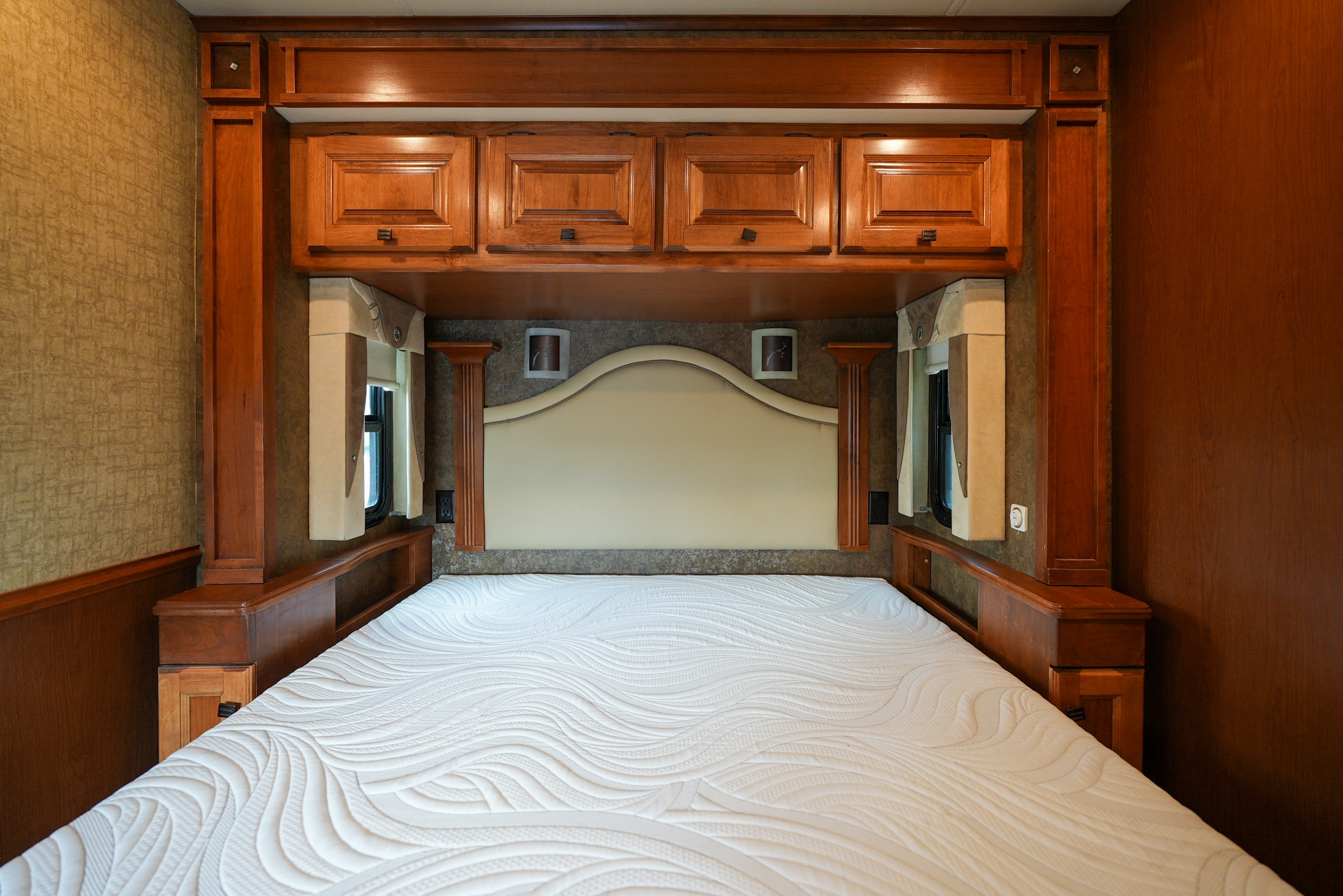 Cozy RV rental bedroom with a comfortable bed, elegant wood cabinets, and upholstered headboard for restful travel.. Allegro Allegro Motorhome 2014