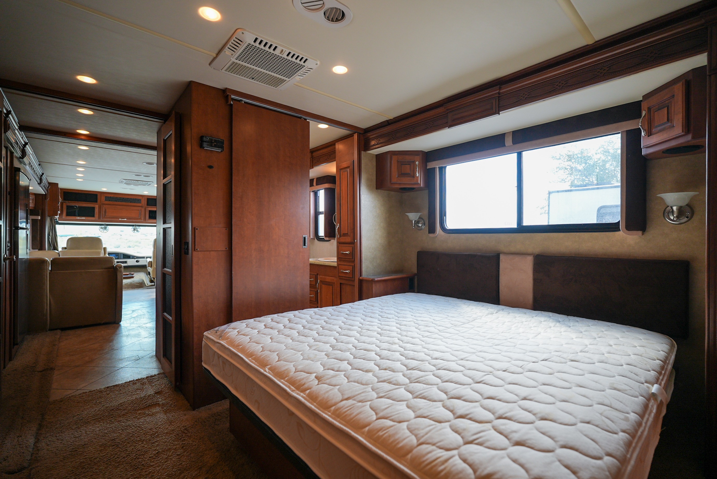 Cozy RV rental bedroom showcasing a comfortable mattress, stylish wood cabinetry, window views, and ample lighting for your travels.. Southwind Southwind Motorhome 2013