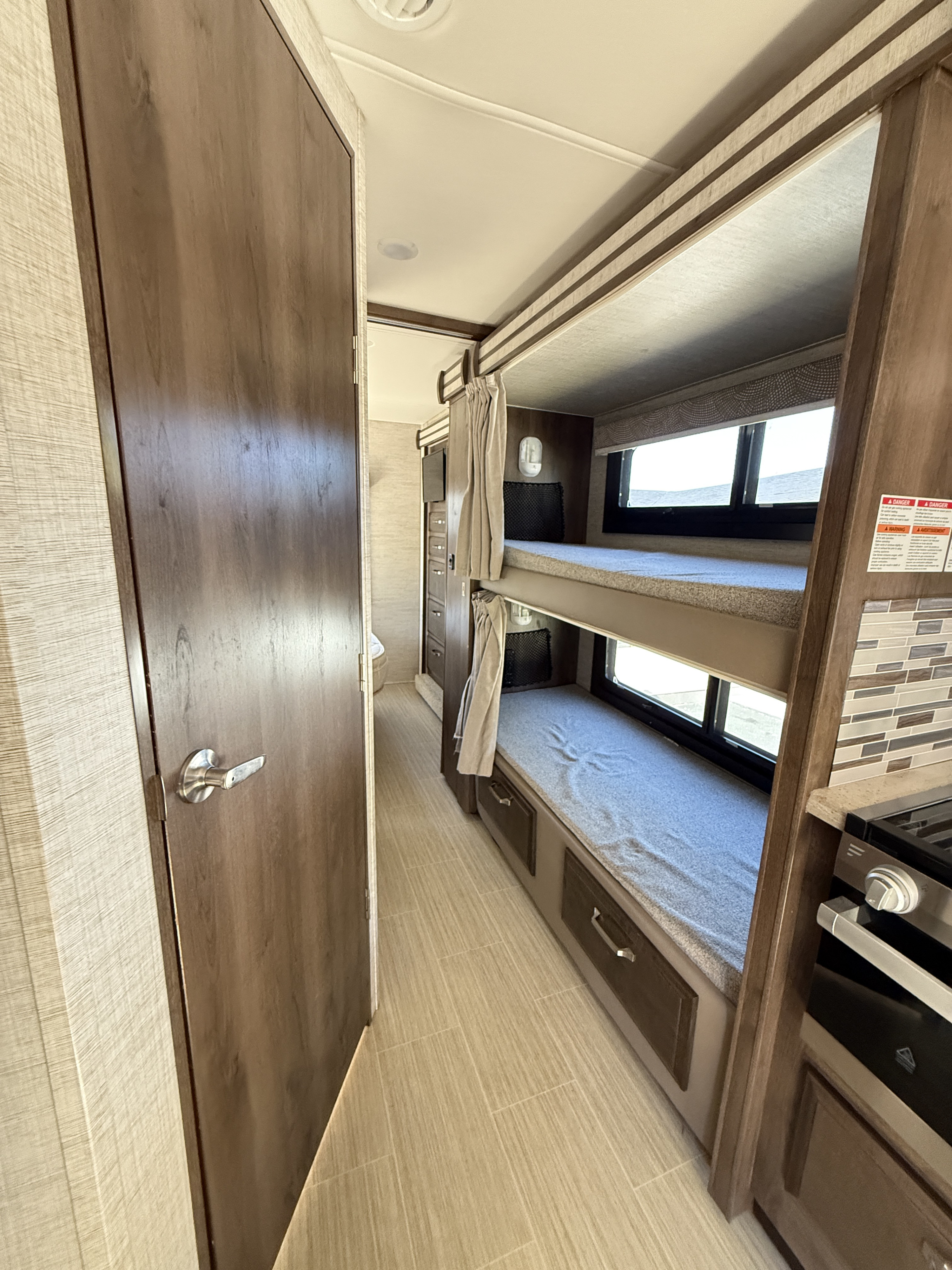 RV rental interior featuring cozy bunk beds with windows, a compact kitchen corner, and a hallway leading to other rooms.. Entegra Coach Esteem 2021