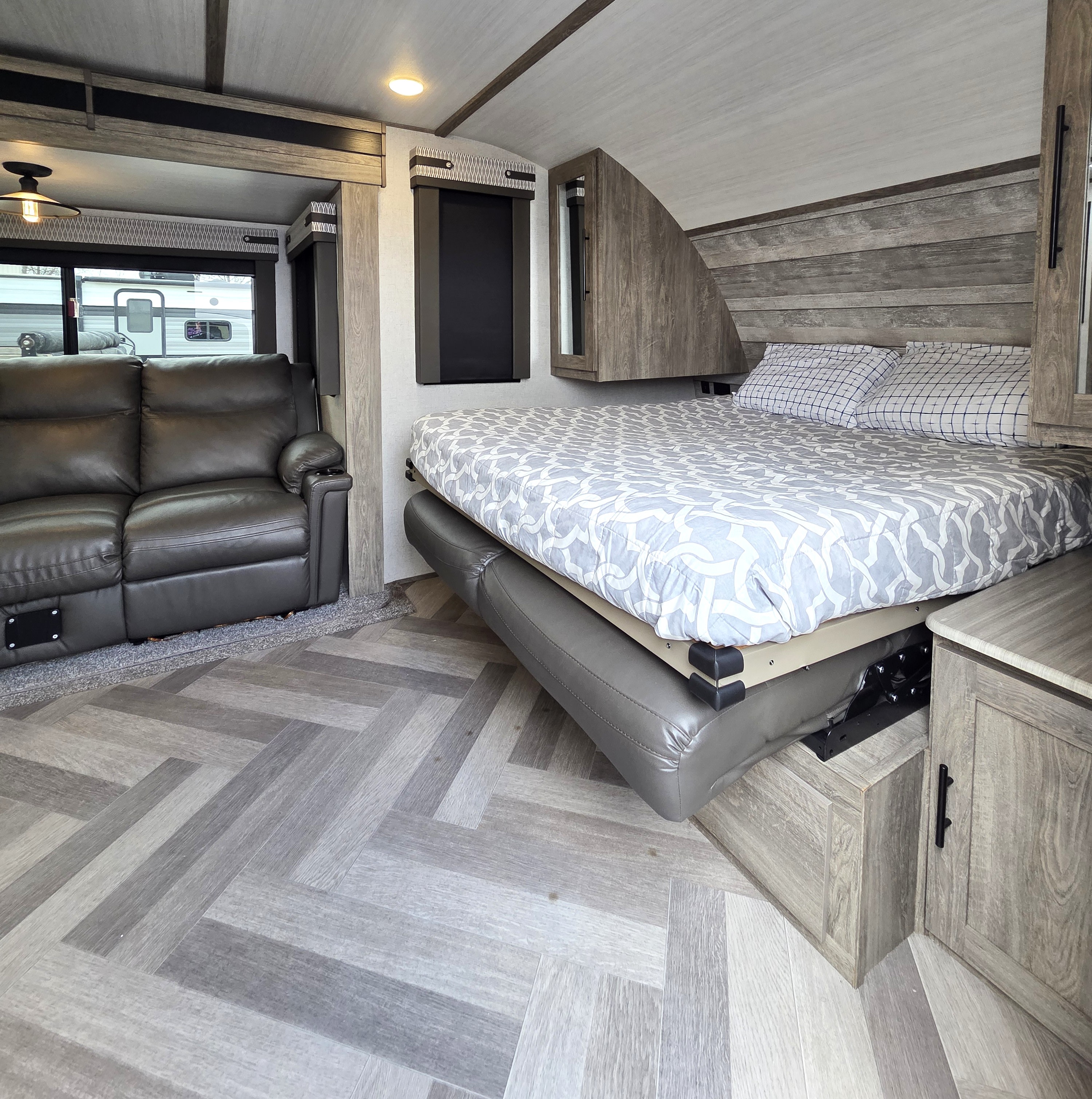 This RV rental offers a modern interior with a dark sofa, a cleverly designed convertible bed, and a stylish herringbone floor.. Forest River Wildwood Heritage Glen HL 2021