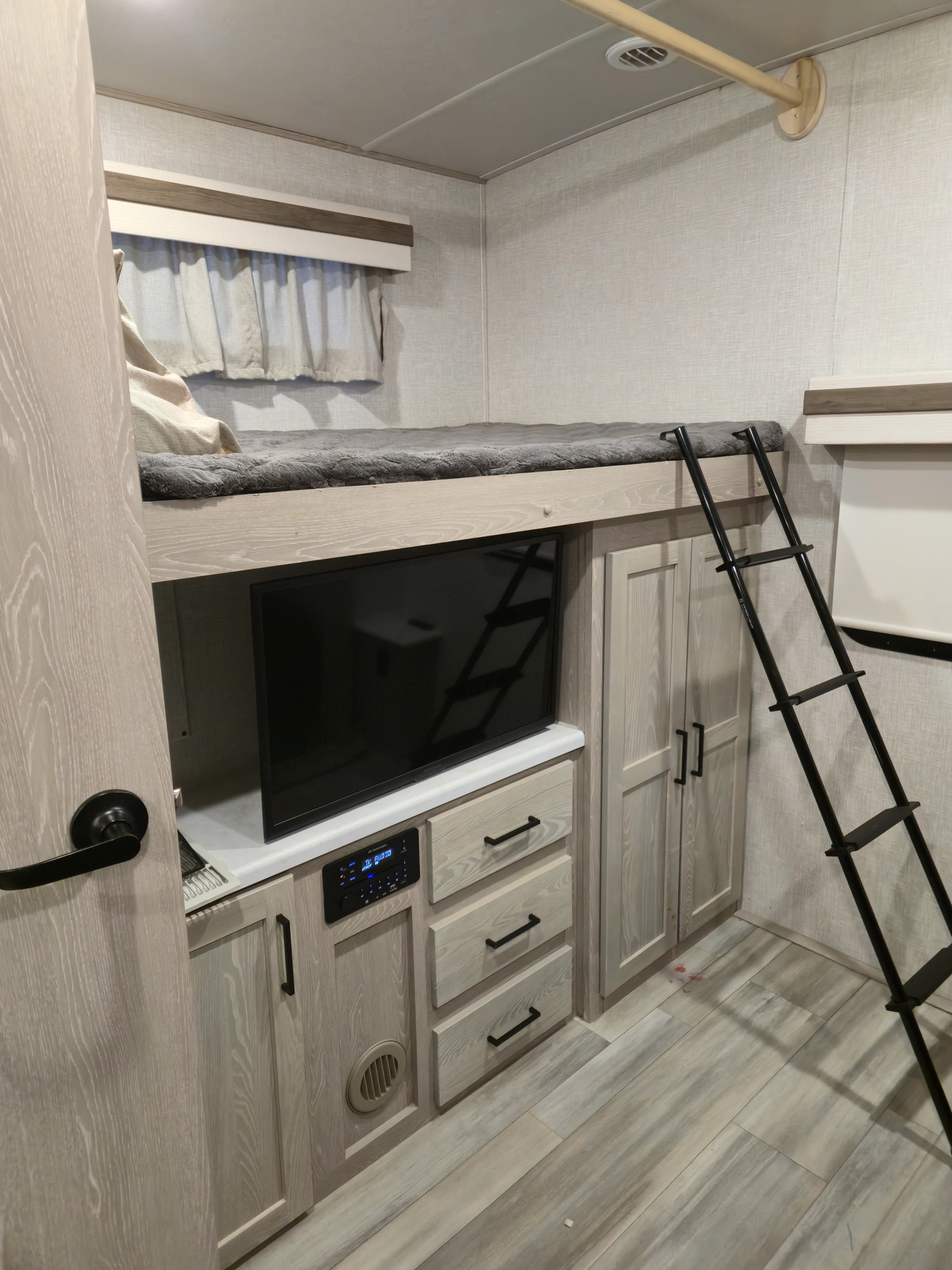 Modern RV rental bunk area features a comfy top bunk, TV, audio system, storage cabinets, and ladder. Light, airy interior.. Forest River Rockwood Signature 2022