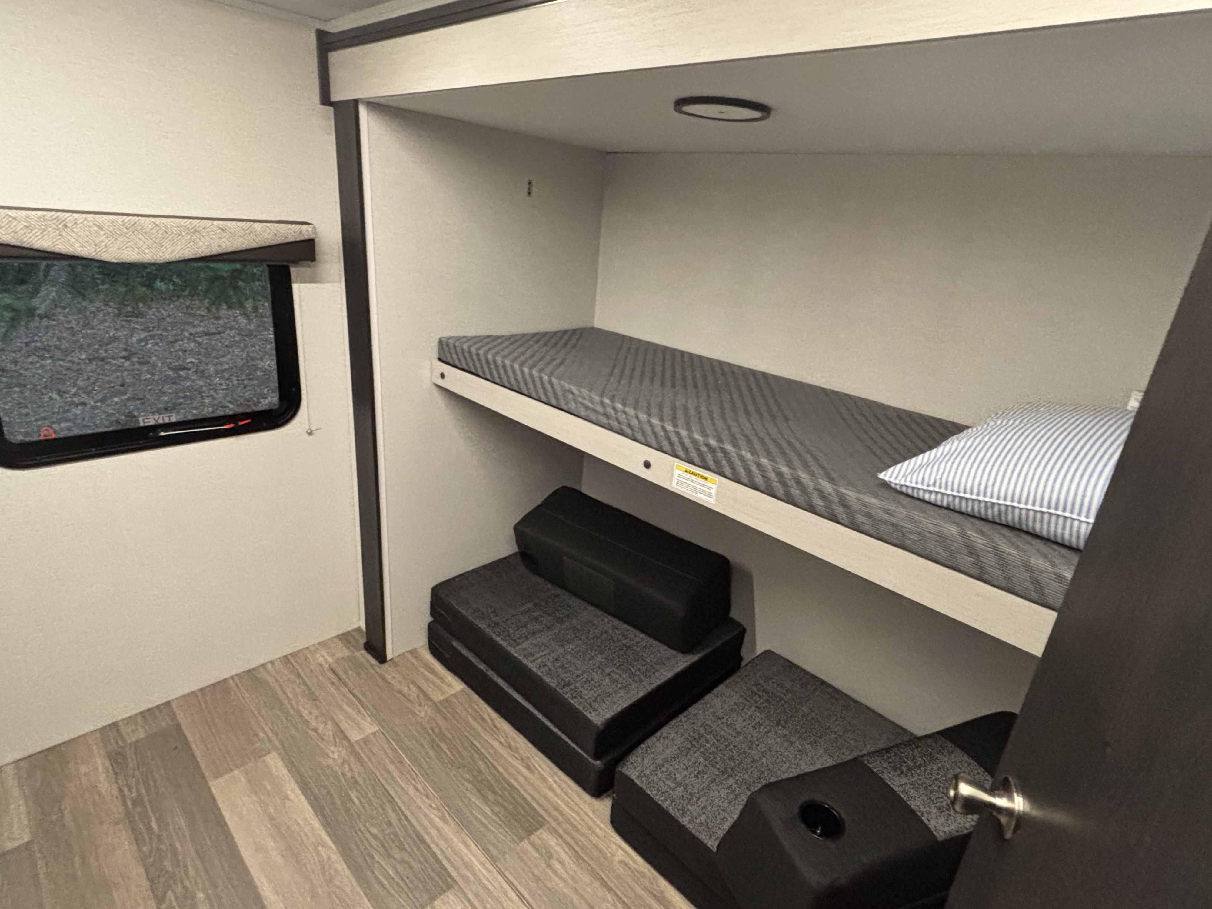 RV rental sleeping area with bunk beds, a window, and versatile seating on wood-look flooring for compact living.. Cruiser RV Shadow Cruiser 2025