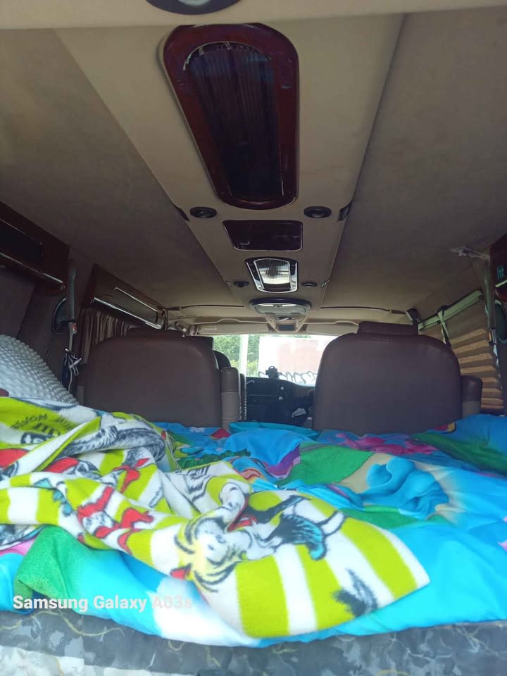 Inside an rv rental: a cozy van interior with a bed, colorful blankets, brown seats, and a detailed overhead console.. Dodge Ram Van 1500 2003