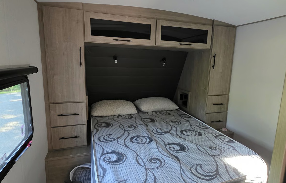 Bright RV rental bedroom featuring a bed with patterned mattress, light wood cabinets, overhead storage, and ample side wardrobes.. Grand Design 2800BH 2026