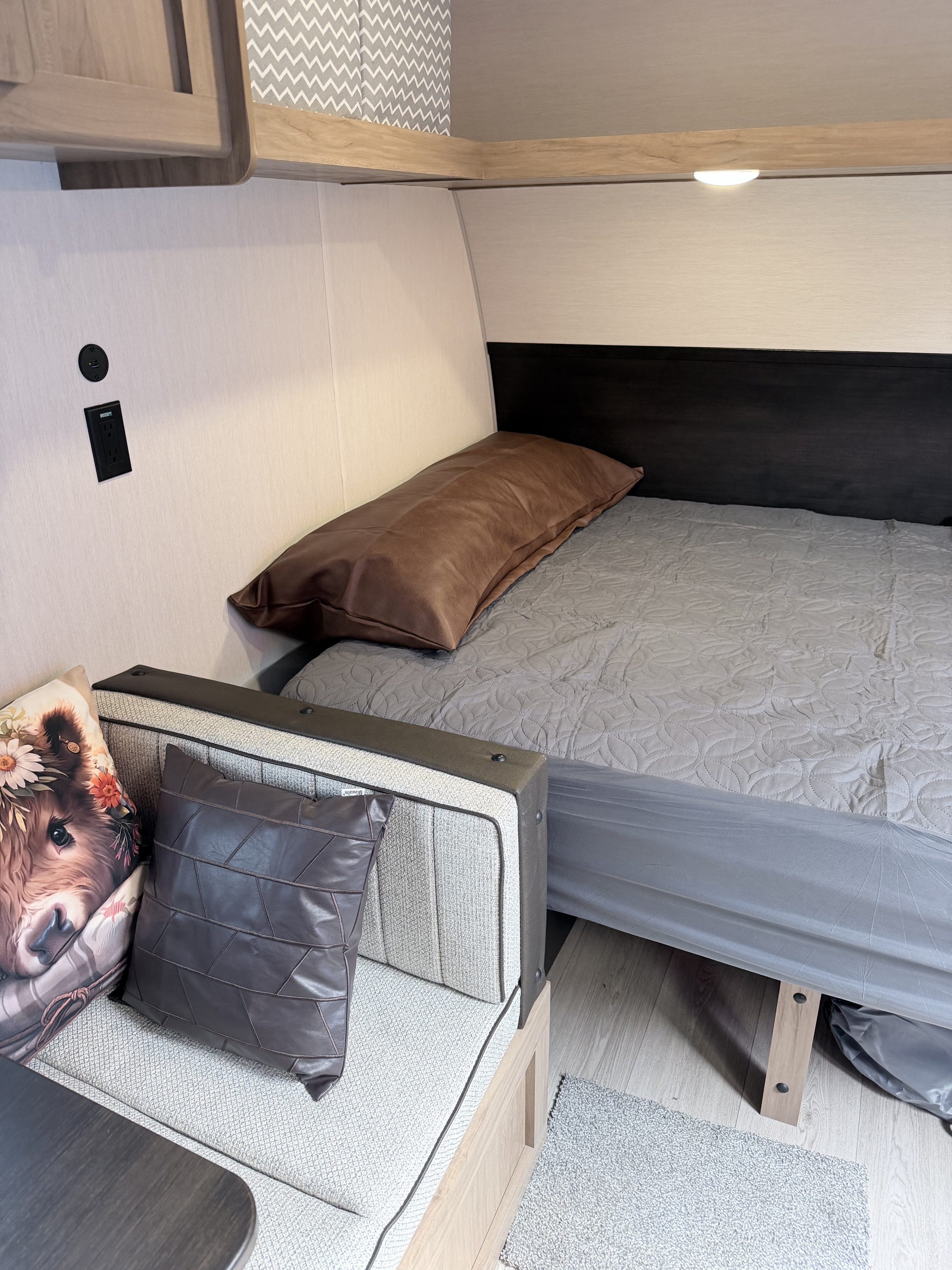 Modern RV rental interior featuring a compact bedroom with a cozy bed, seating, and convenient power outlets.. Forest River Cherokee Wolf Pup 2025
